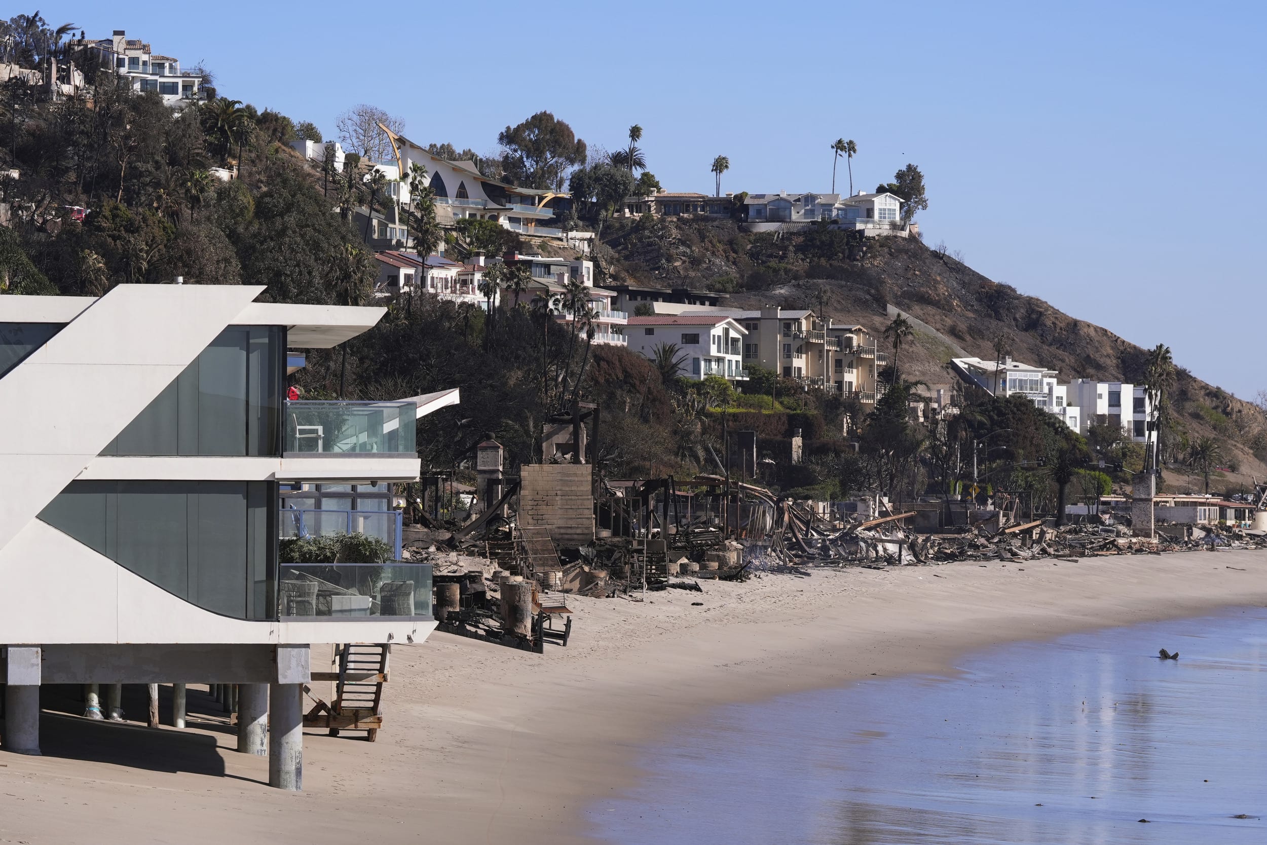 Image: A home stands next to properties destroyed by the Palisades Fire in Malibu, Calif.