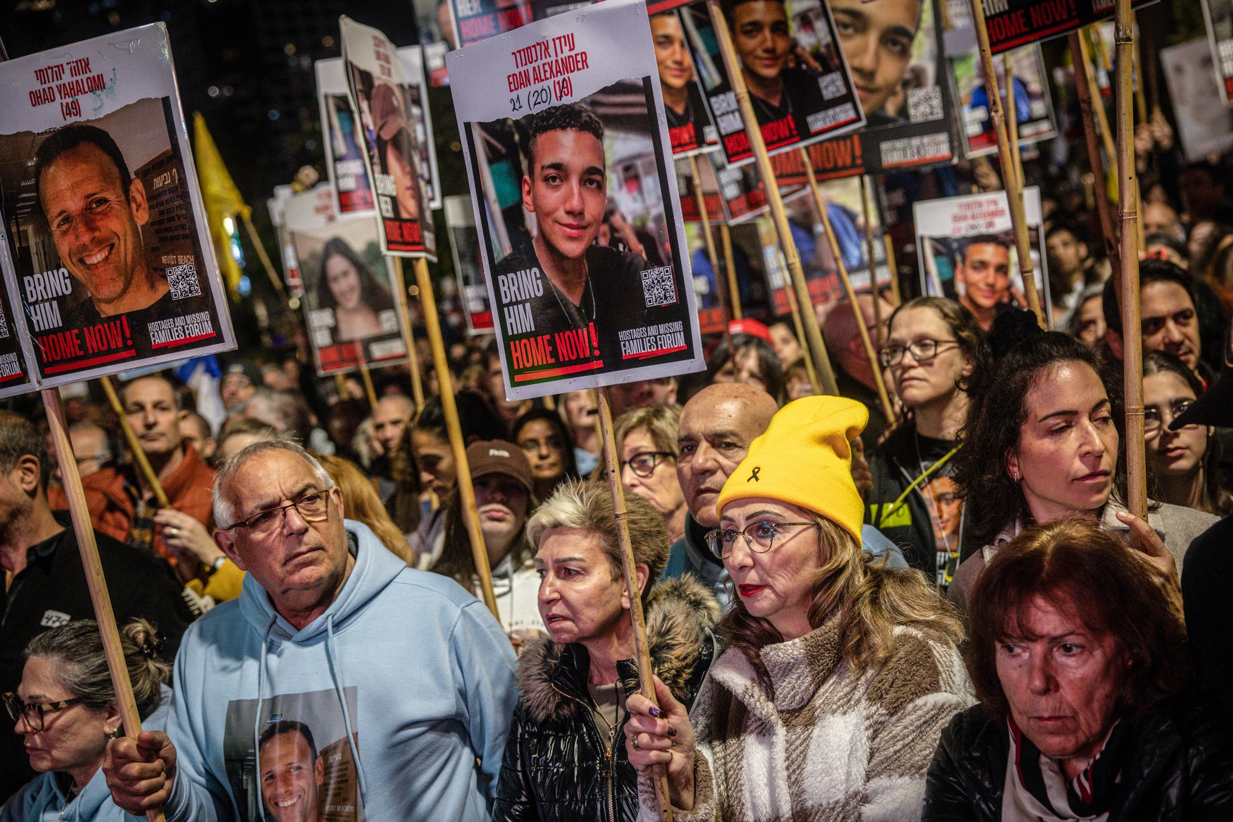 People hold signs with pictures of hostages held in Gaza.