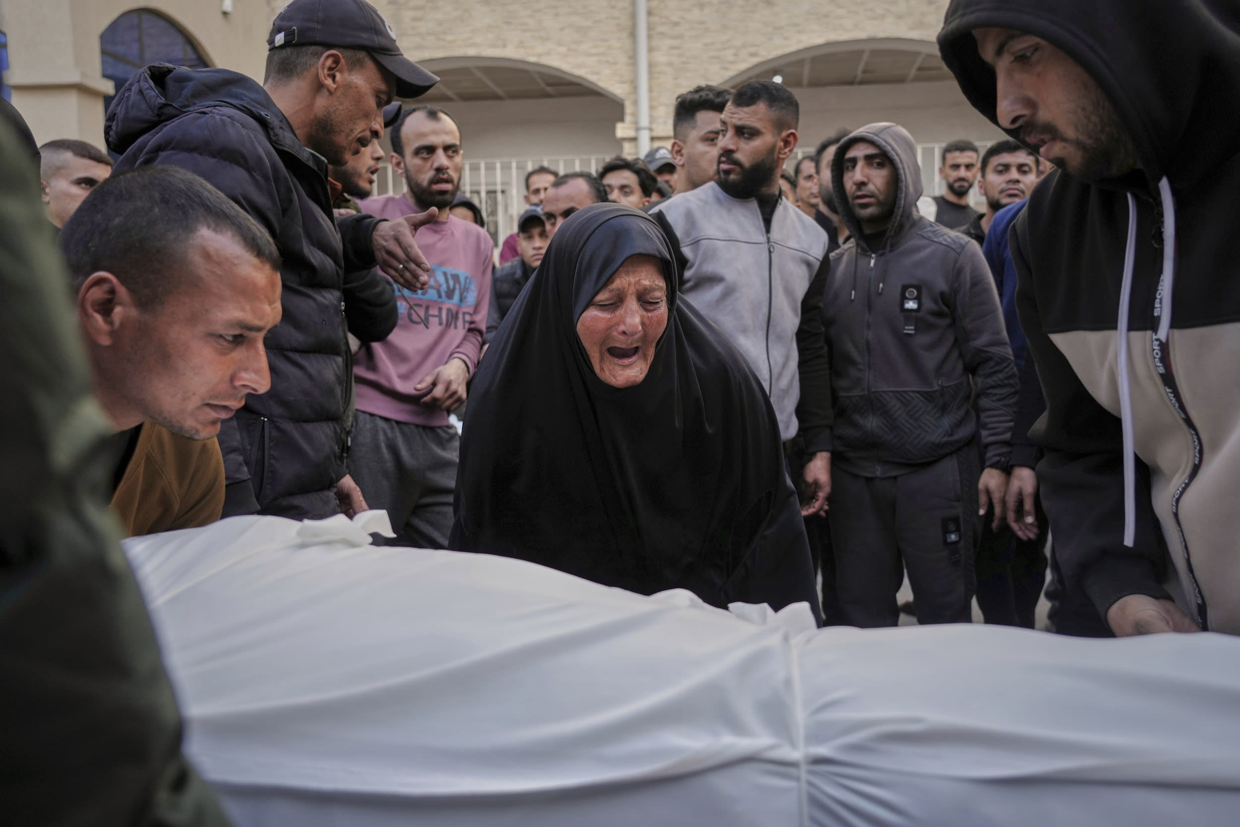 A woman reacts over the body of a person killed.