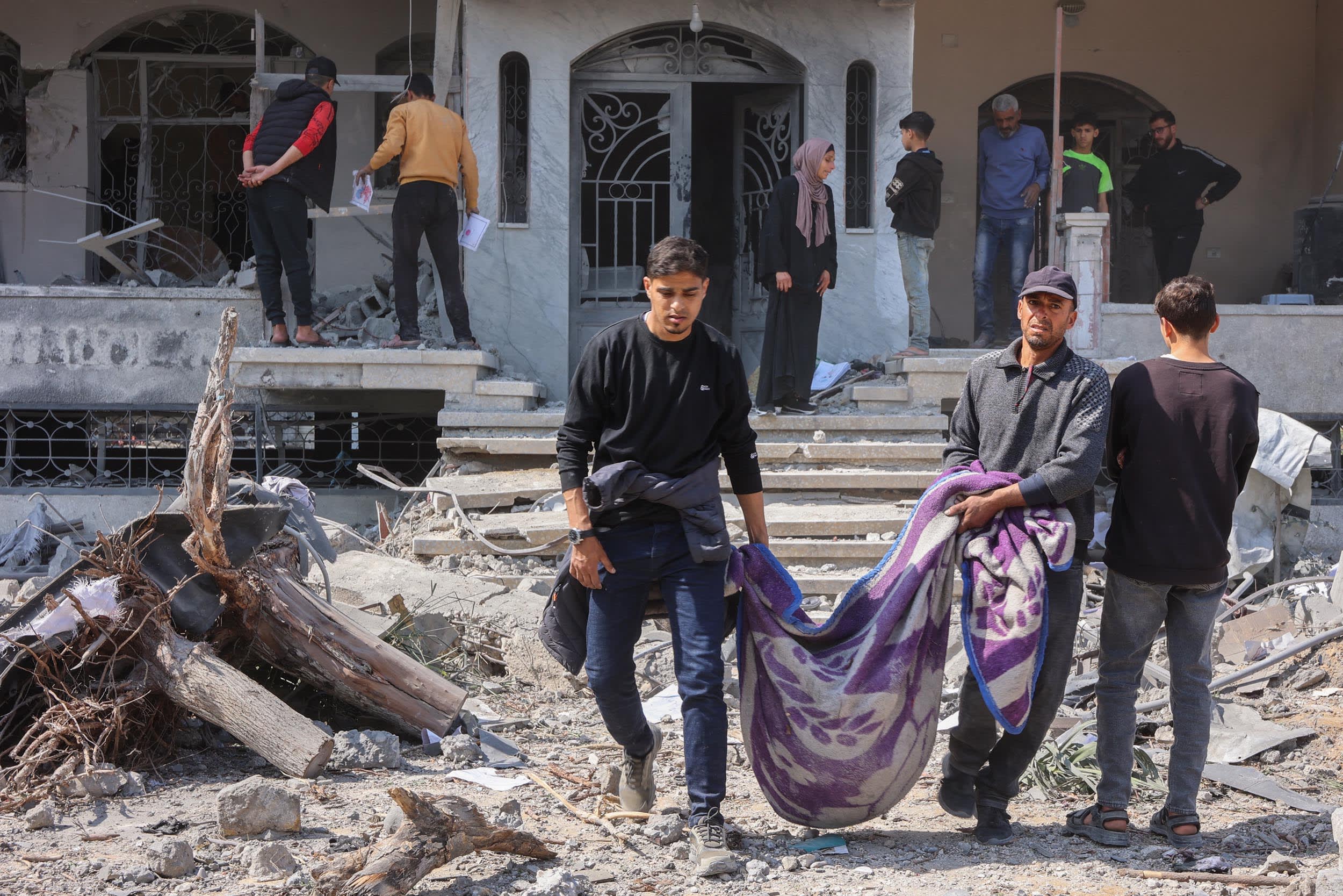 Palestinians carry a body pulled from the rubble of the Qrayqea family house, destroyed in Israeli strikes