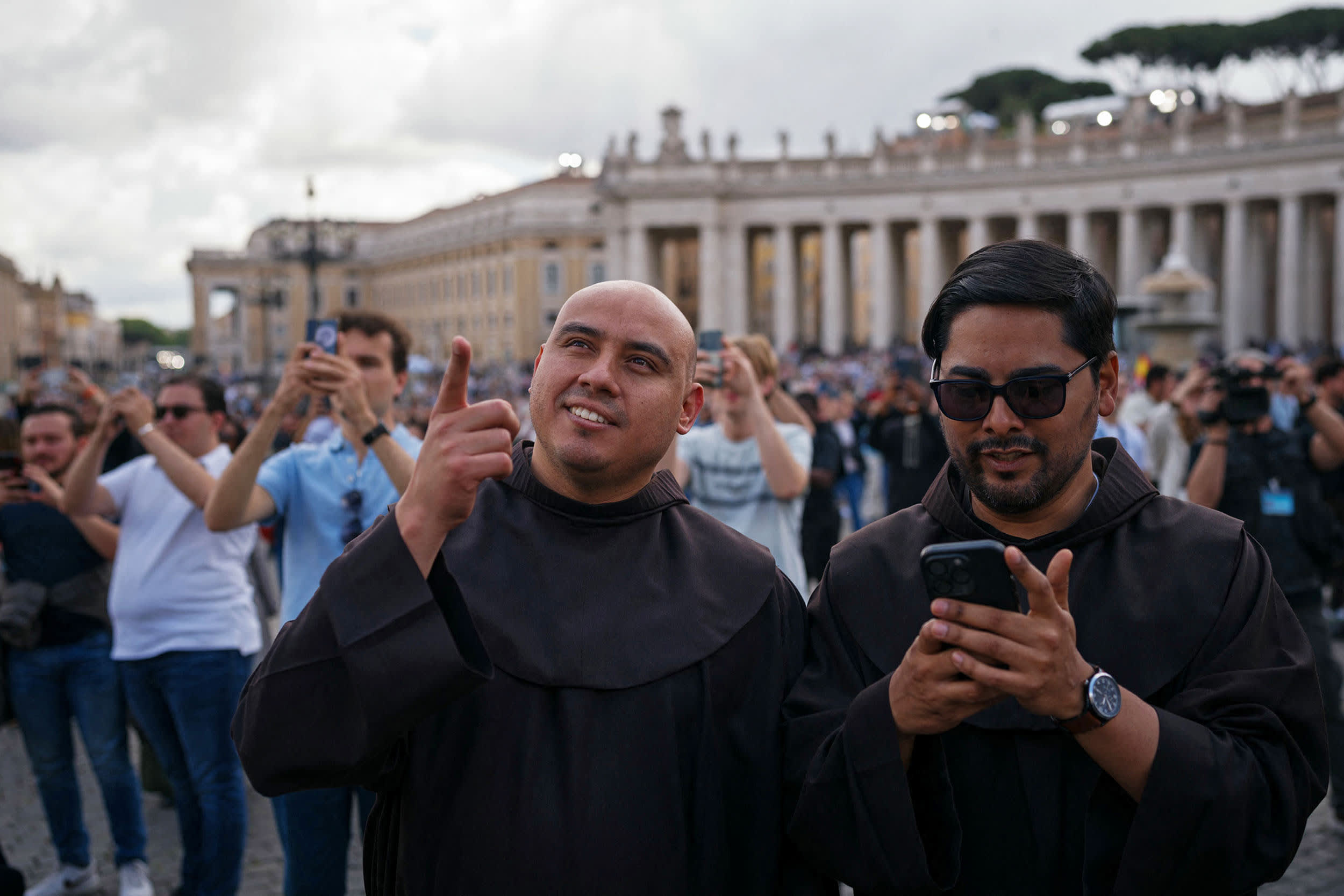 Priests stand on St Peter's Square after black smoke billowed from a chimney over the Sistine Chapel, on the second day of the conclave, in the Vatican on May 8, 2025. 