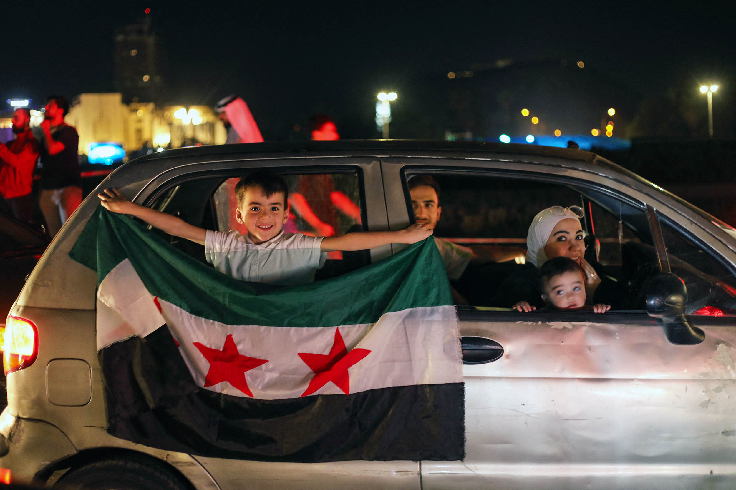 A young boy holds a Syria flag from a car in Damascus' Omeyyad square