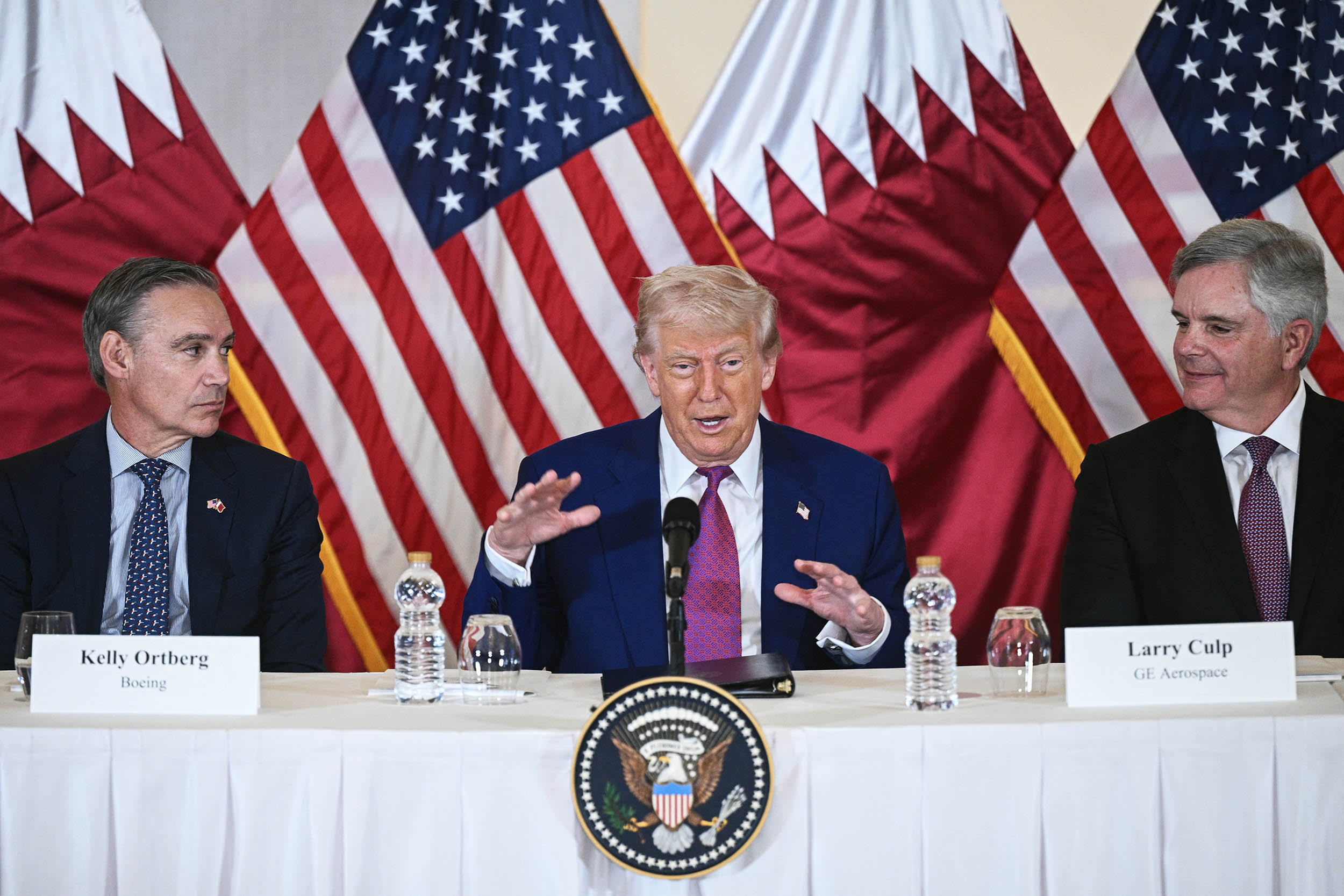 President Donald Trump (C) is flanked with Boeing CEO Kelly Ortberg (L) and CEO of GE Aerospace Larry Culp during a breakfast with business leaders in Doha.