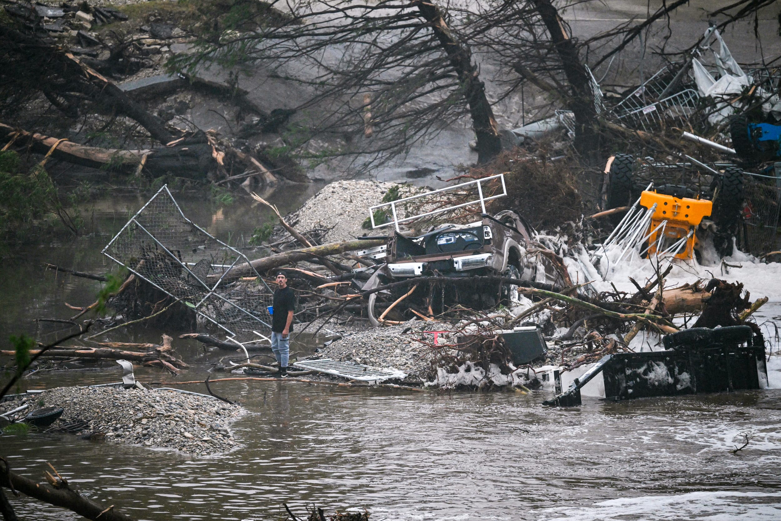 A member of the public stands next to overturned vehicles.