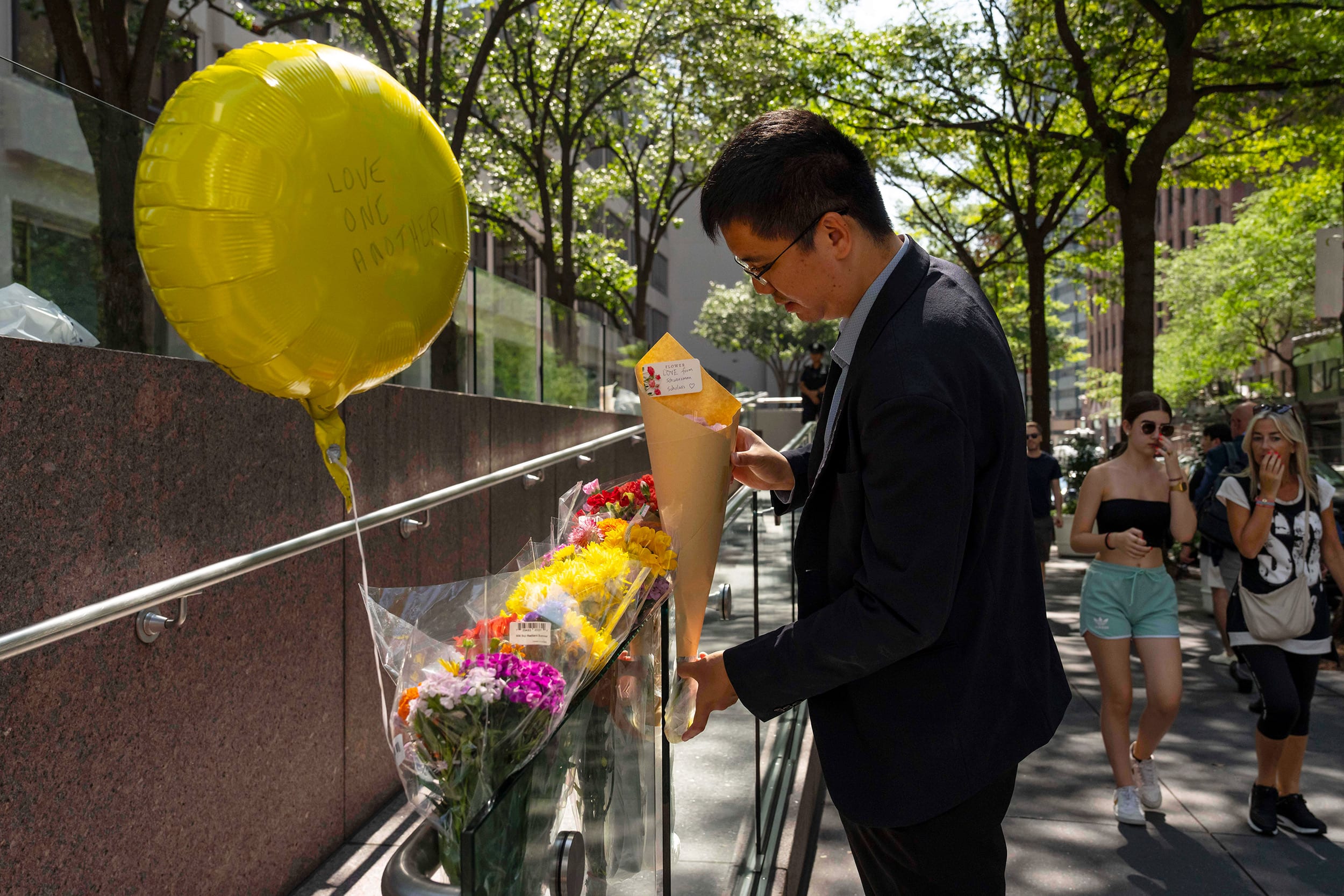 A person leaves flowers at a make shift memorial