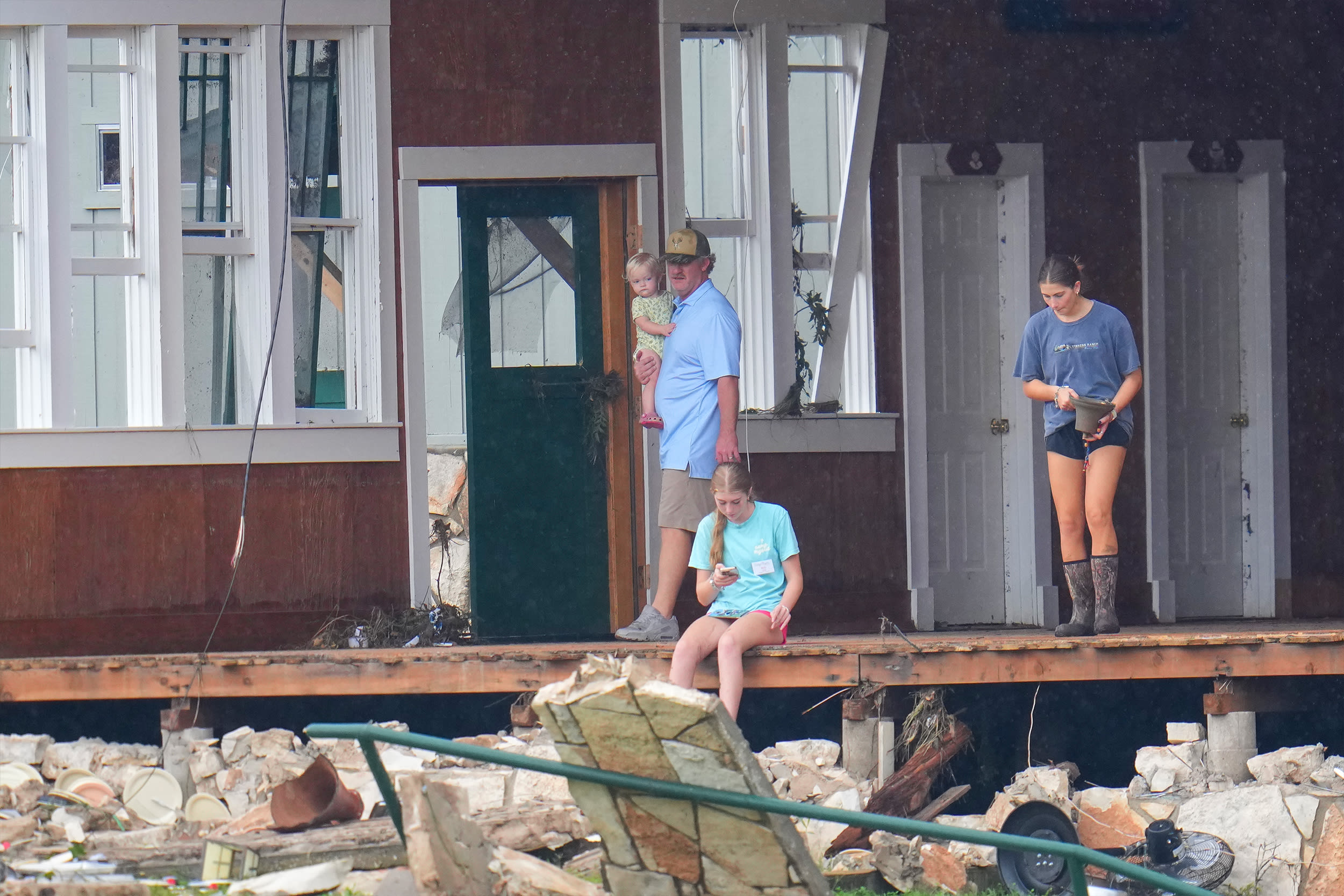 A person salvages a bell from the main building at Camp Mystic along the banks of the Guadalupe River after a flash flood swept through the area Sunday, July 6, 2025, in Hunt, Texas.