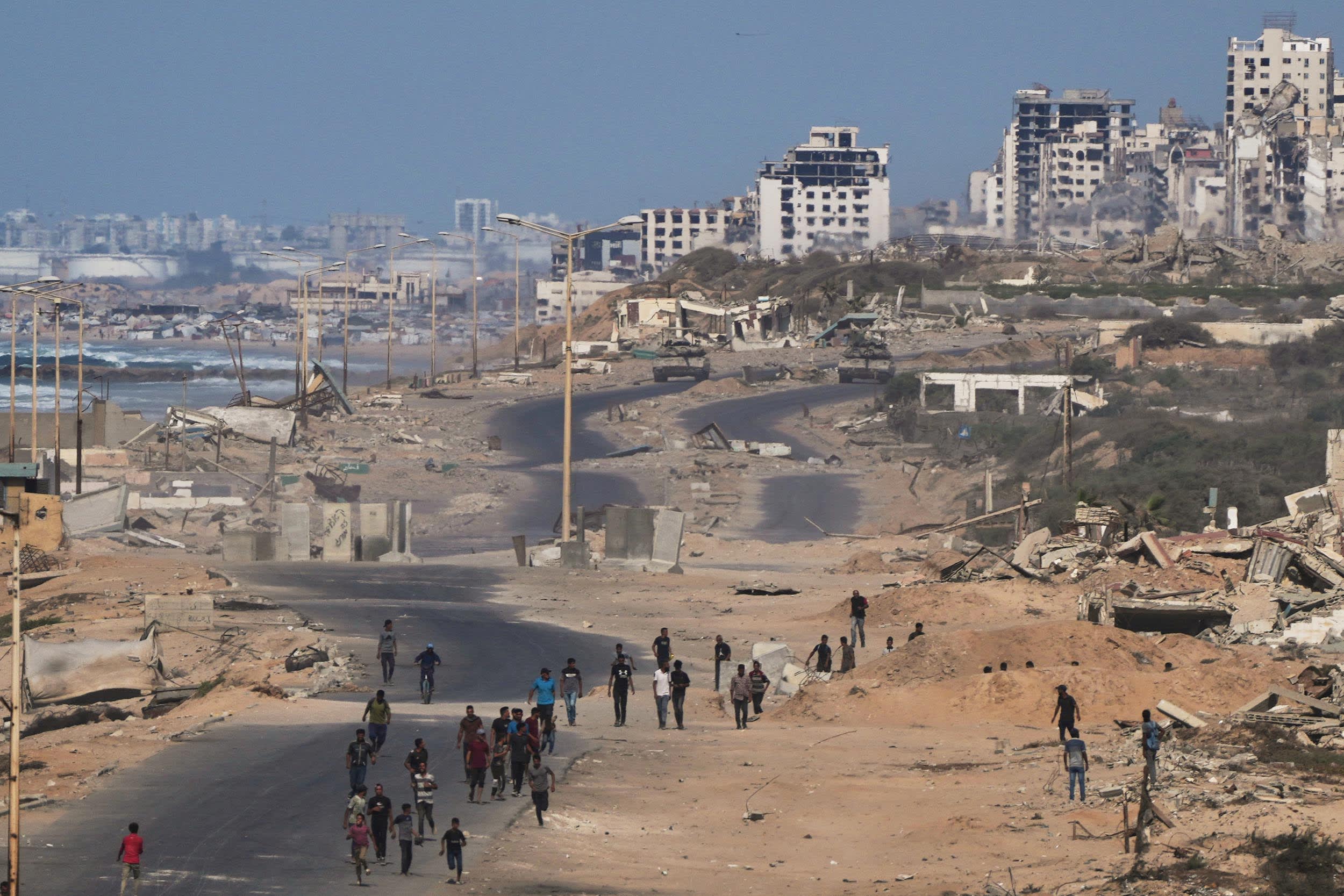 Israeli tanks block the beach road to Gaza City as displaced Palestinians walk on the coastal road near Wadi Gaza on Thursday, Oct. 9, 2025.
