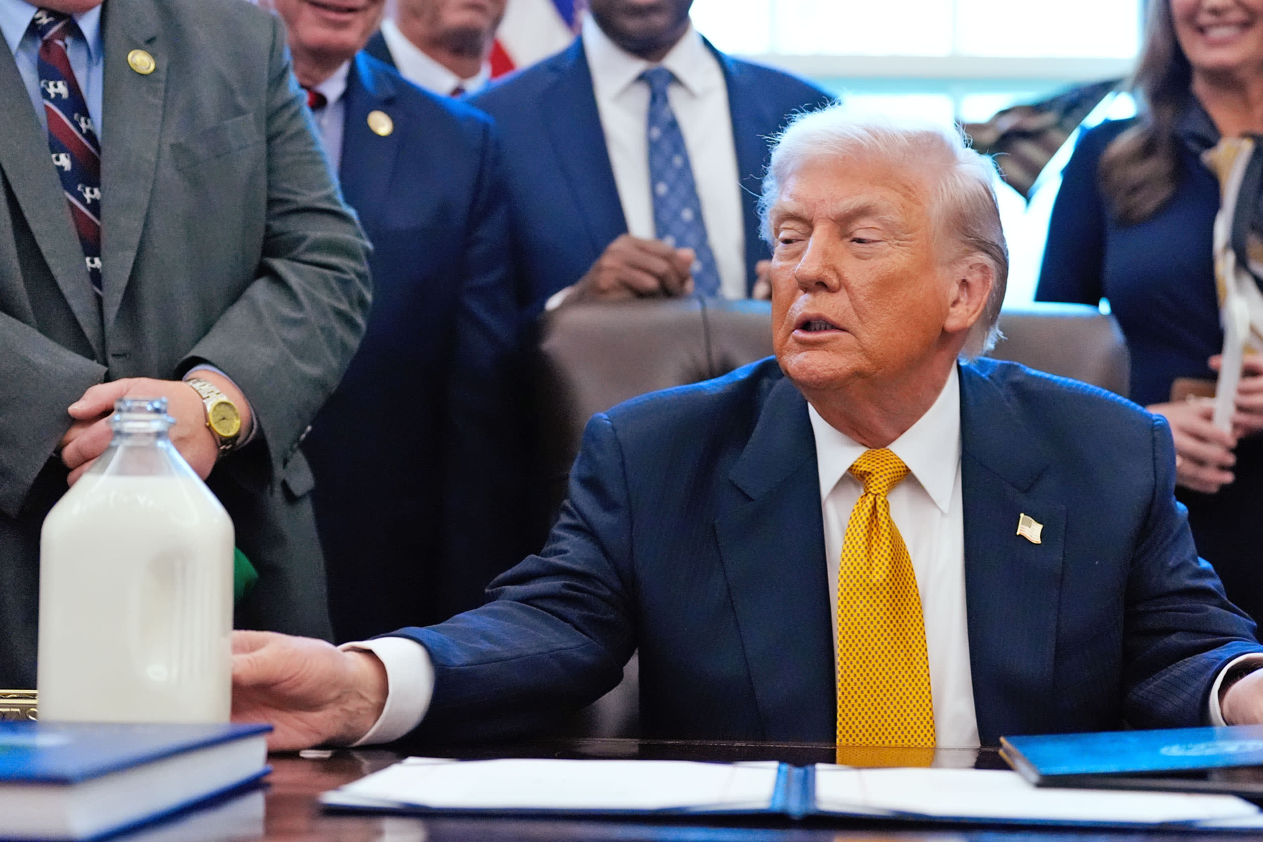 President Donald Trump touches a container of milk as he speaks in the Oval Office of the White House, Wednesday, Jan. 14, 2026.