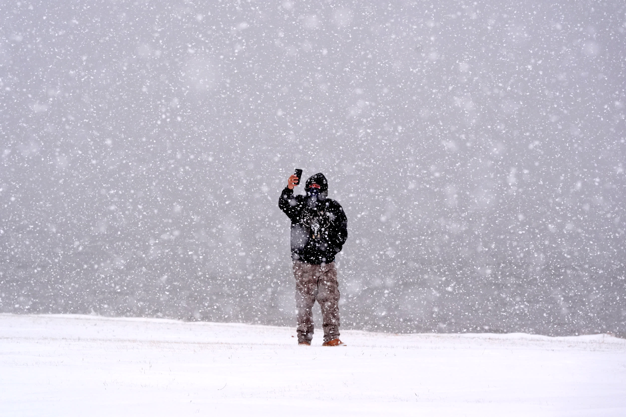 A man taking photos of heavy snow falling.