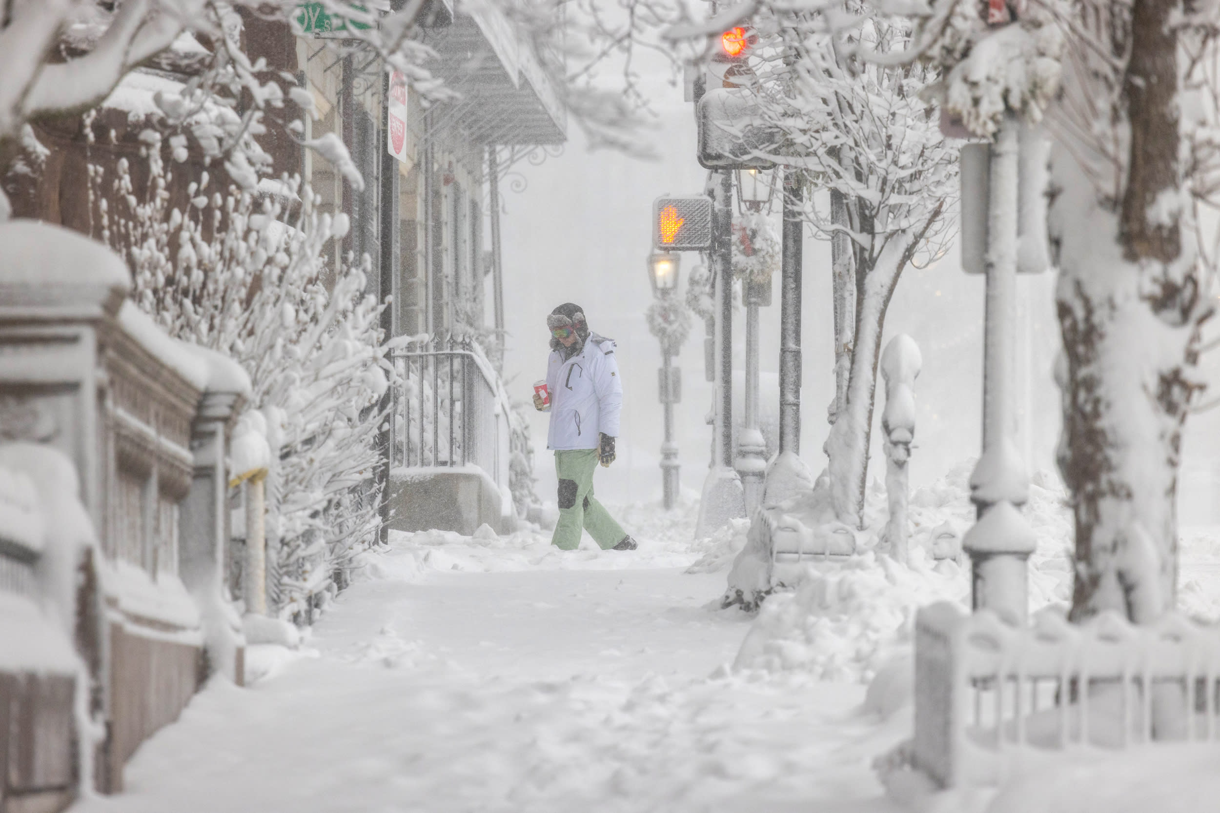 A person walking in the middle of a blizzard in Boston.