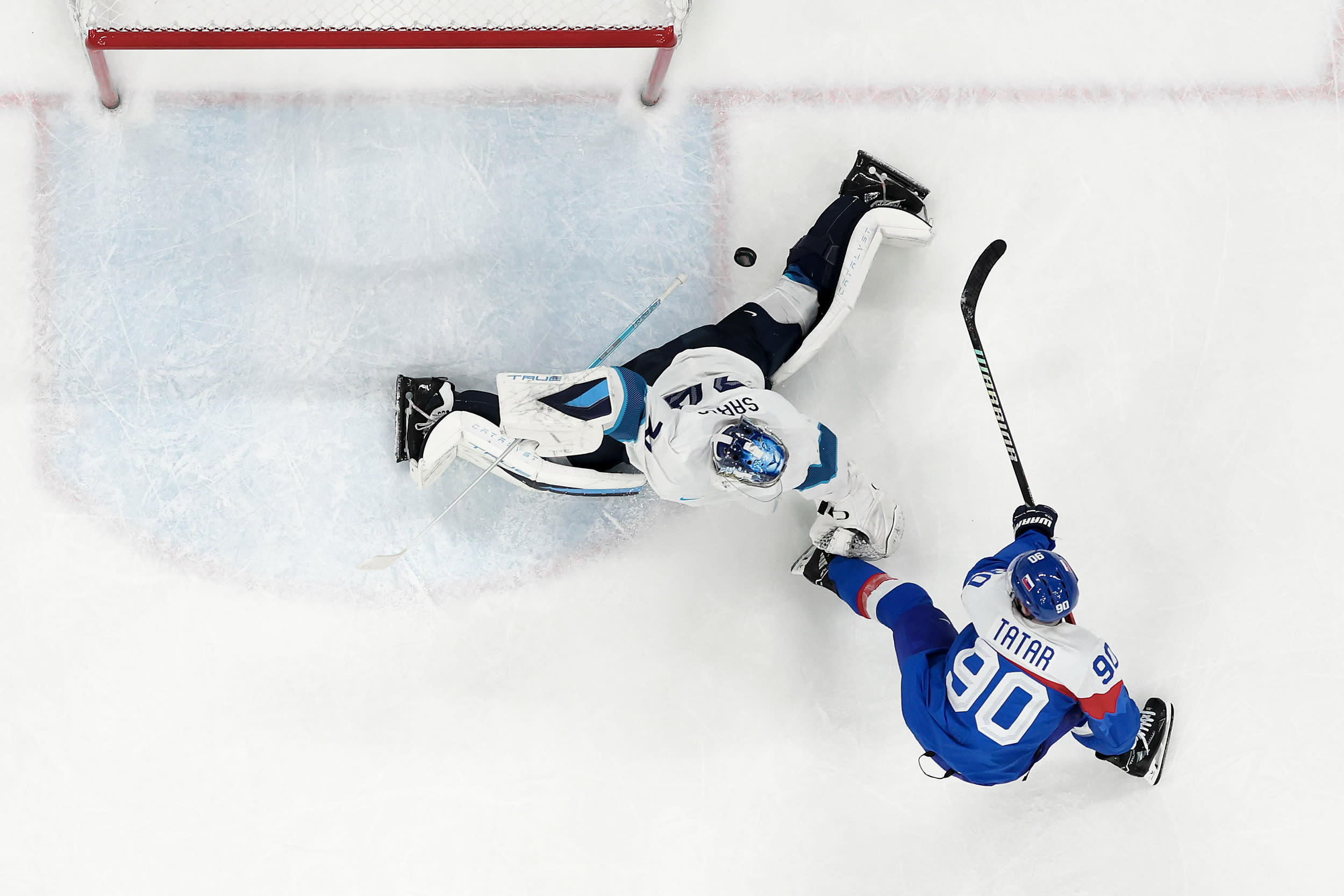 An overhead view of a puck as it flies past a goalie during a hockey game.