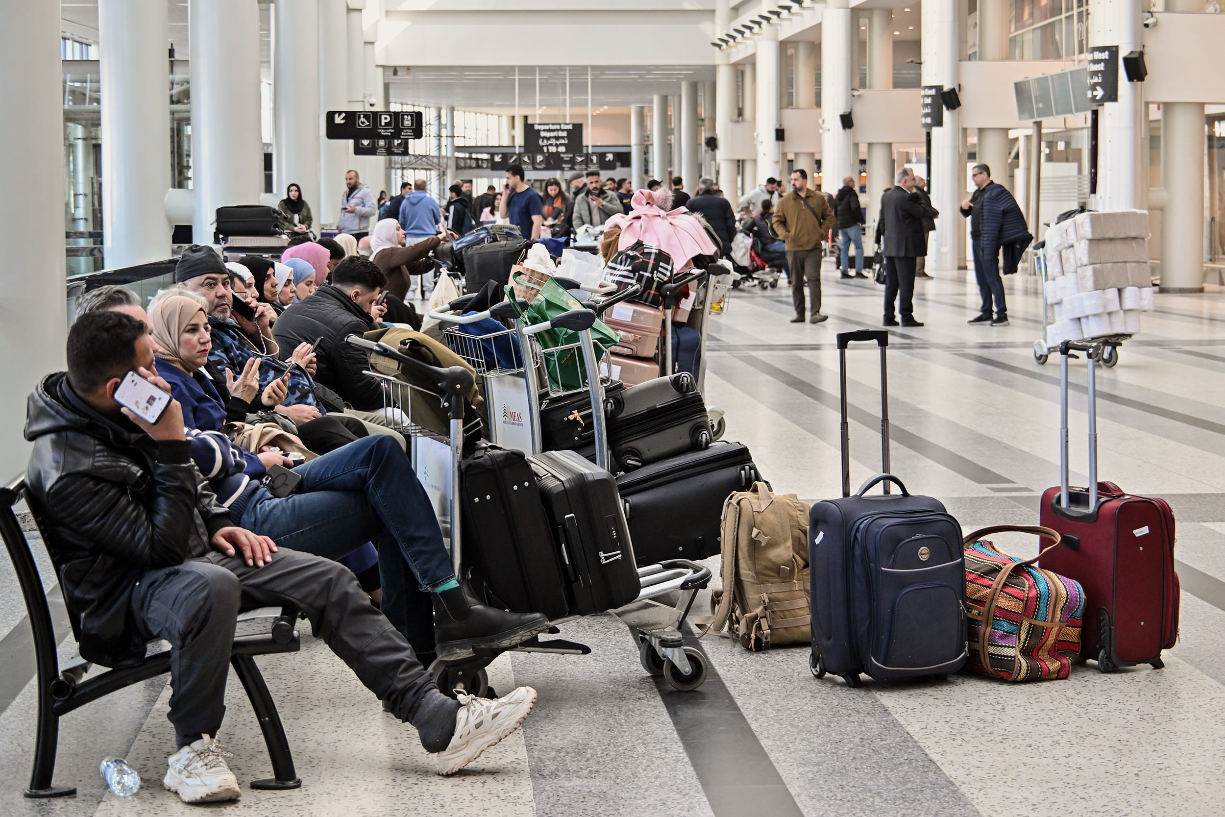 Passengers seated in a crowded airport terminal.