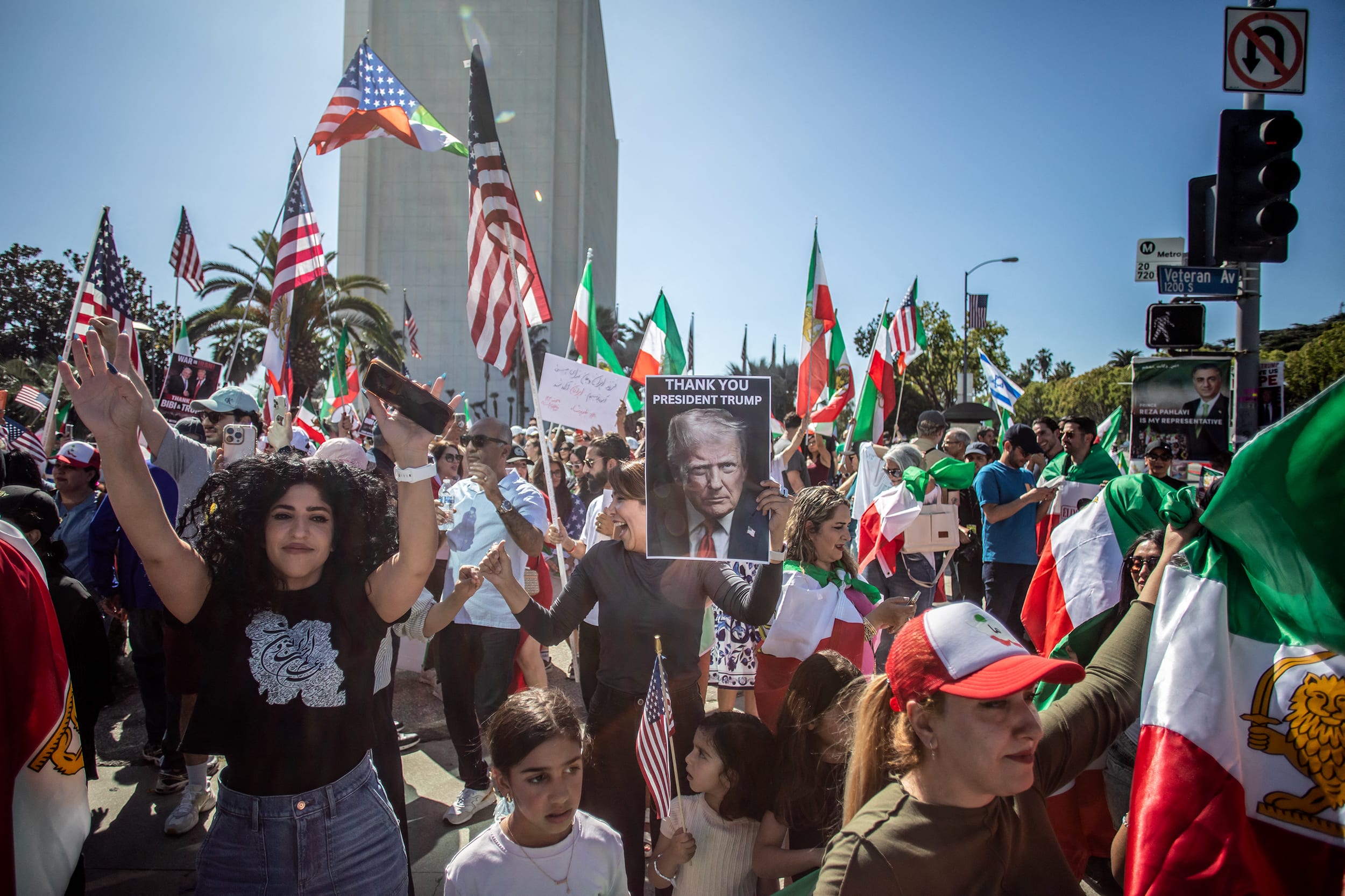 A large crowd of people waving Iranian national flags gathered outdoors in California.