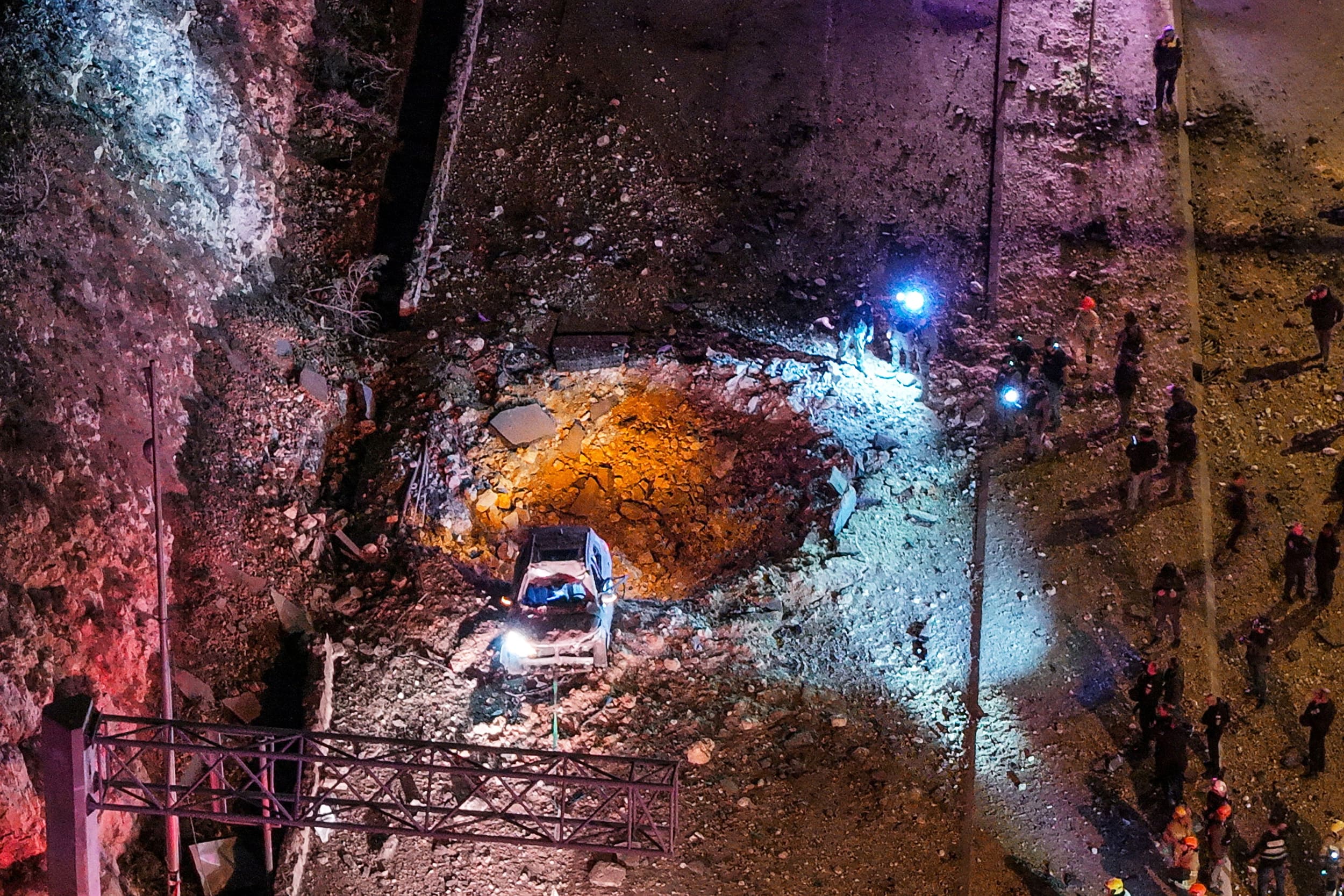 A drone view of Israeli emergency responders working at the scene of an Iranian missile strike on a road, in Jerusalem