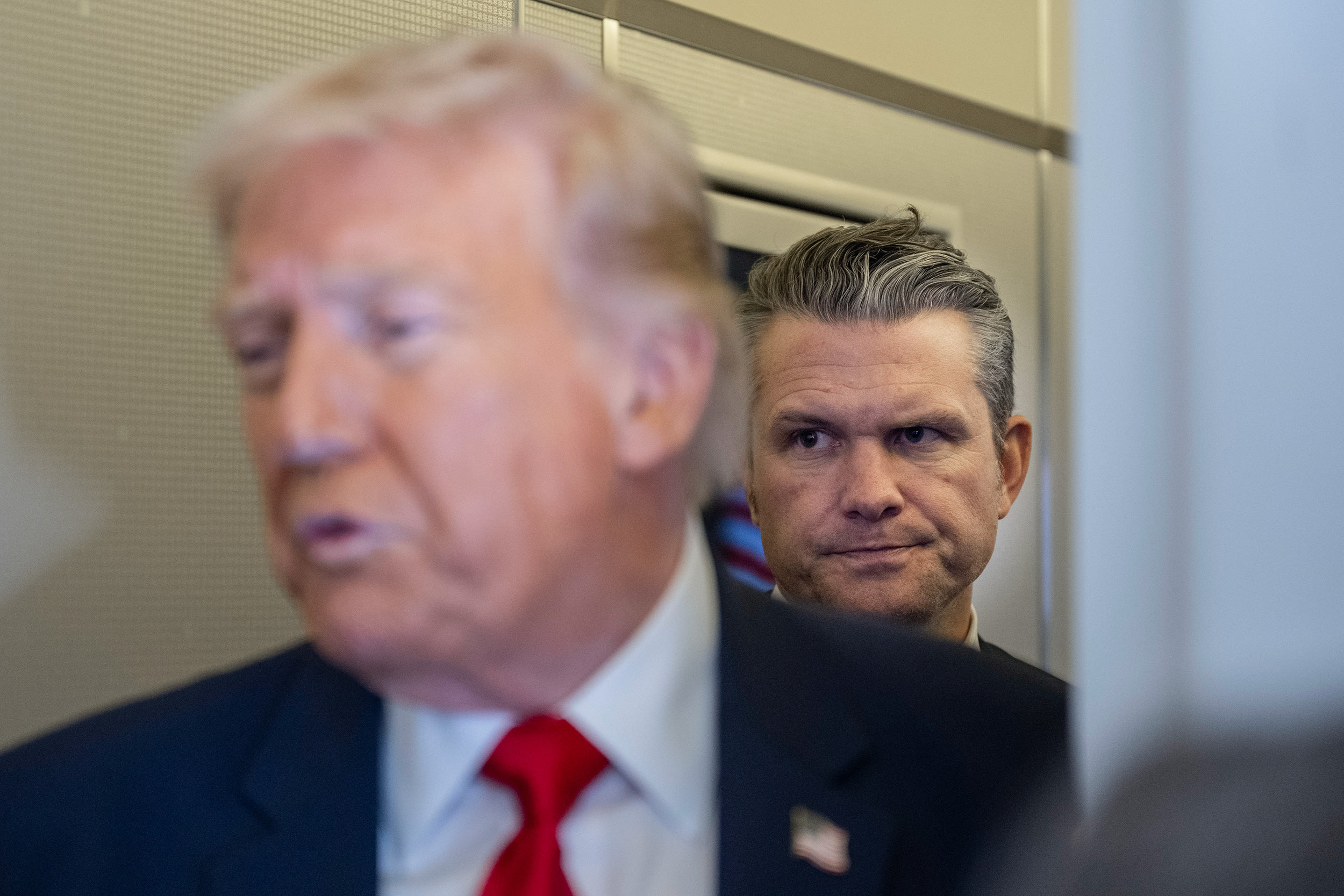 Donald Trump appears in soft focus in front of Pete Hegseth aboard Air Force One.