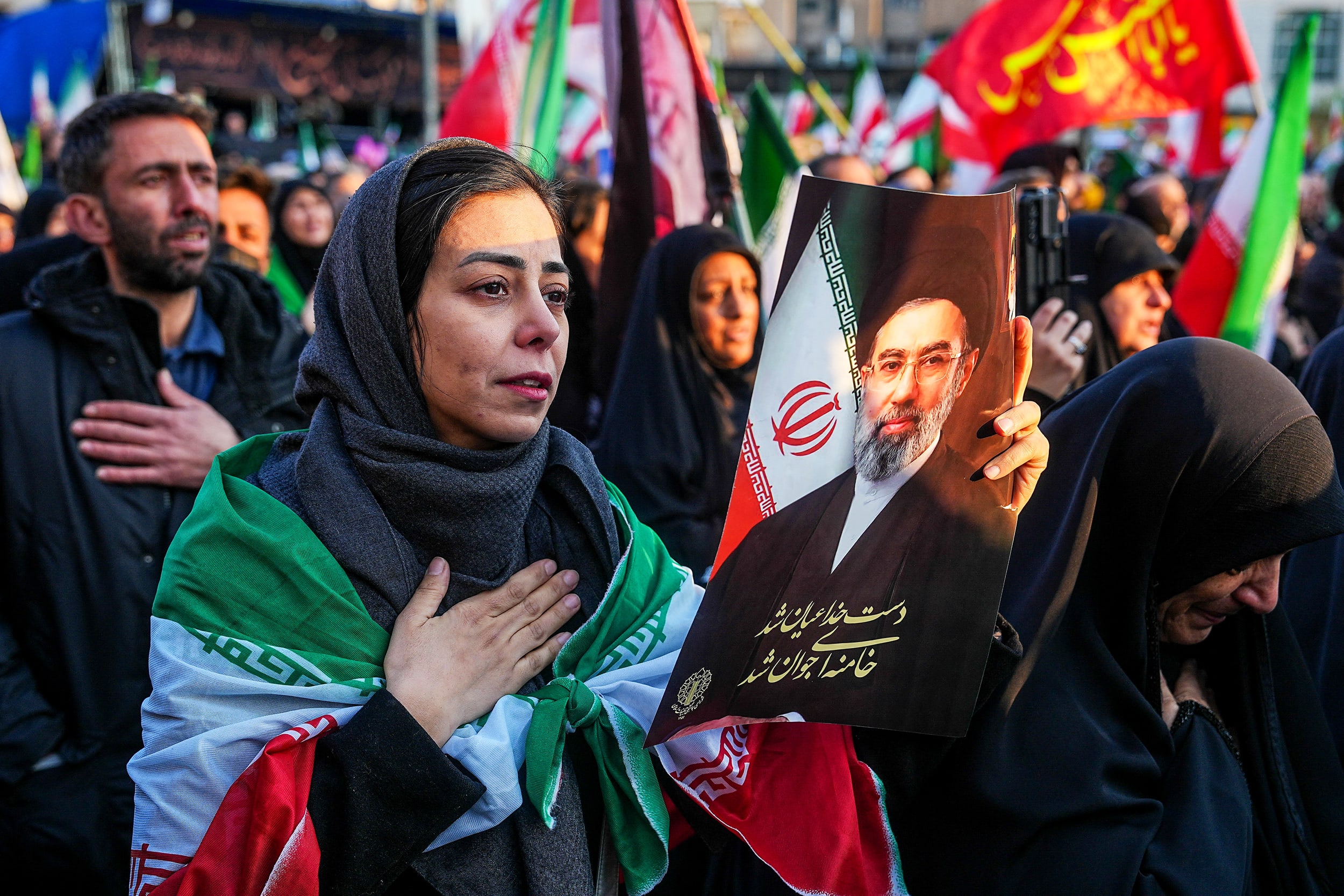 Image: A woman holds a picture of Iran's new Supreme Leader Ayatollah Mojtaba Khamenei
