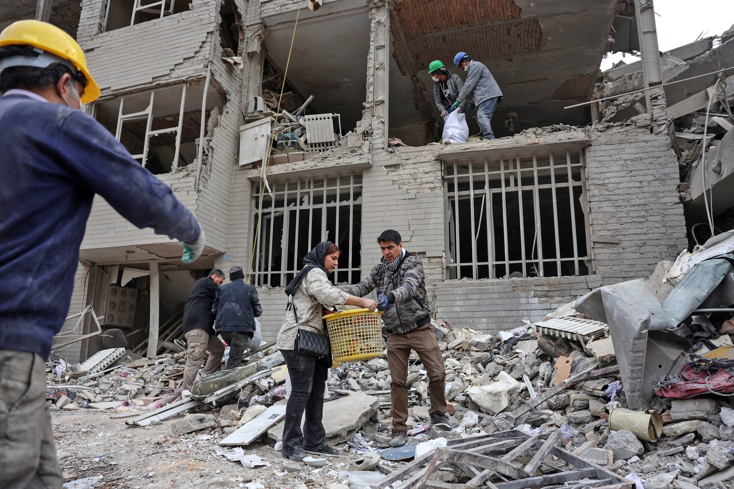 Iranians collect belongings from the rubble of a damaged residential building in Tehran