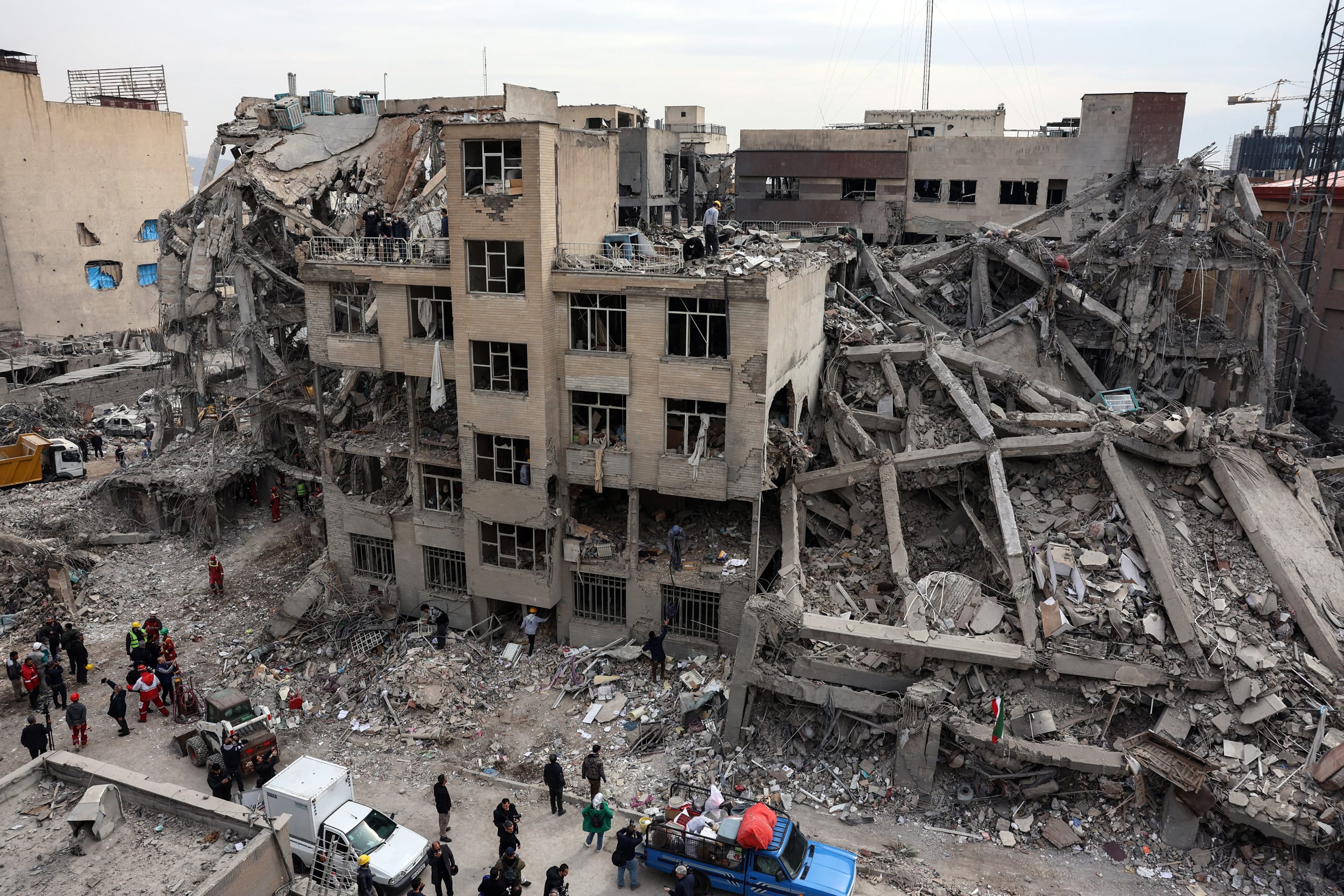 Rescue workers gather outside a damaged residential building in Tehran