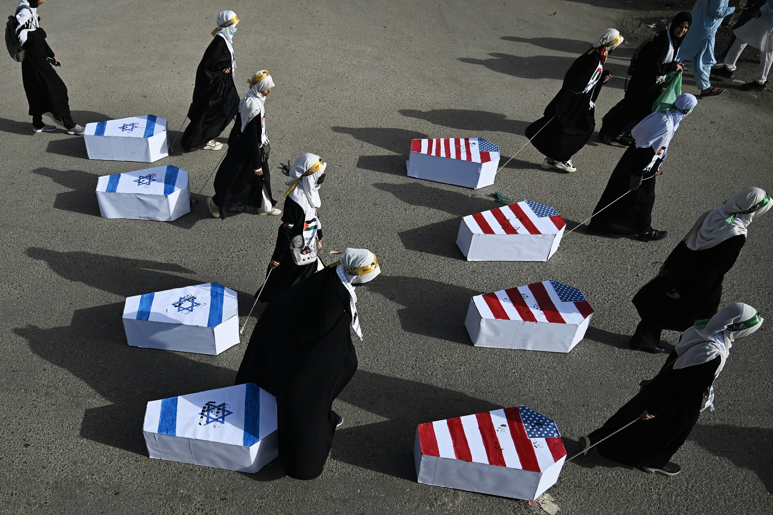 Pakistani Shia Muslim women drag coffins wrapped with Israeli and U.S. flags during a rally to mark Al-Quds Day, the last Friday of the Islamic holy fasting month of Ramadan, in Karachi on March 13, 2026.