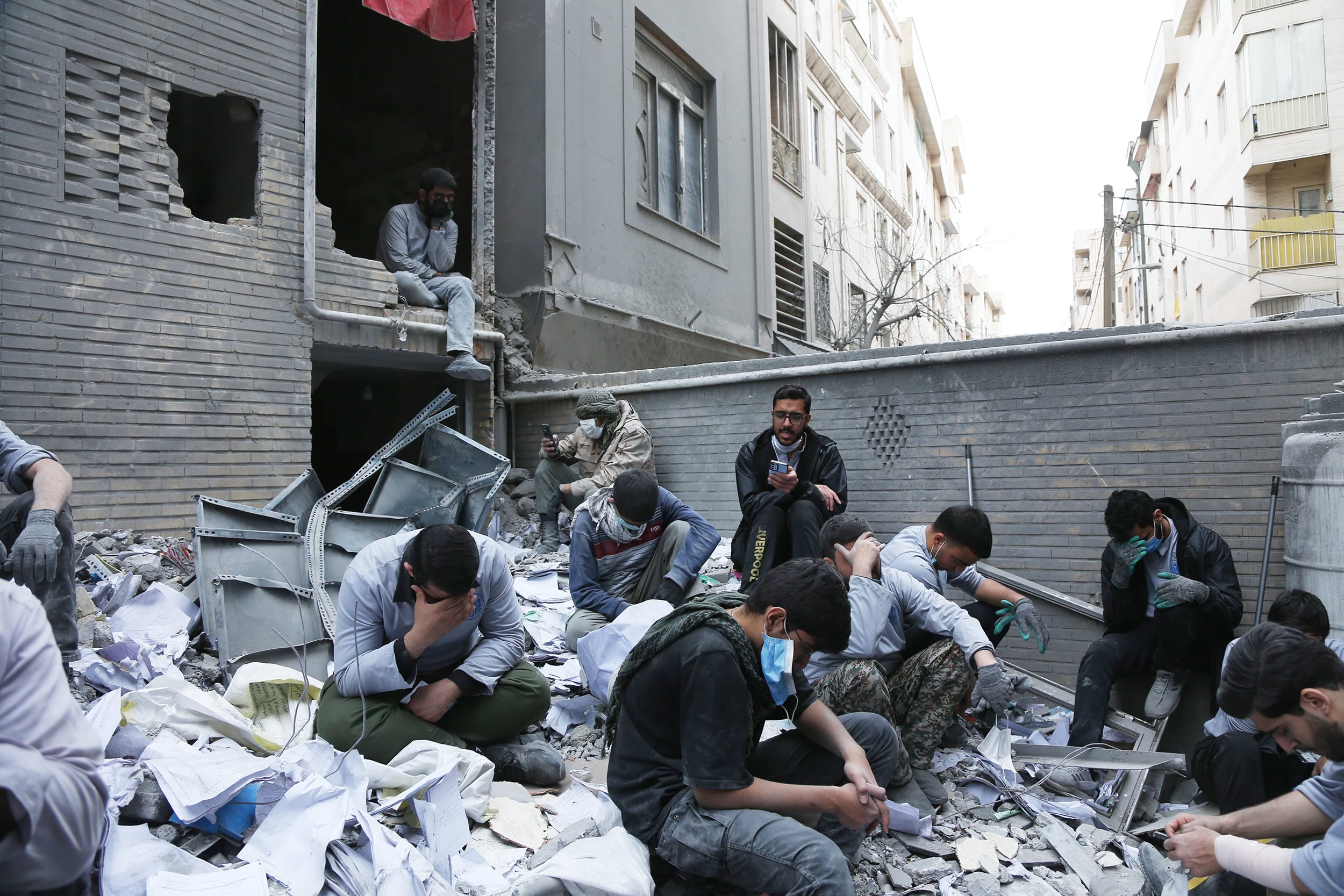 Local men grieve in the rubble of a destroyed residential building in Tehran on March 15, 2026.