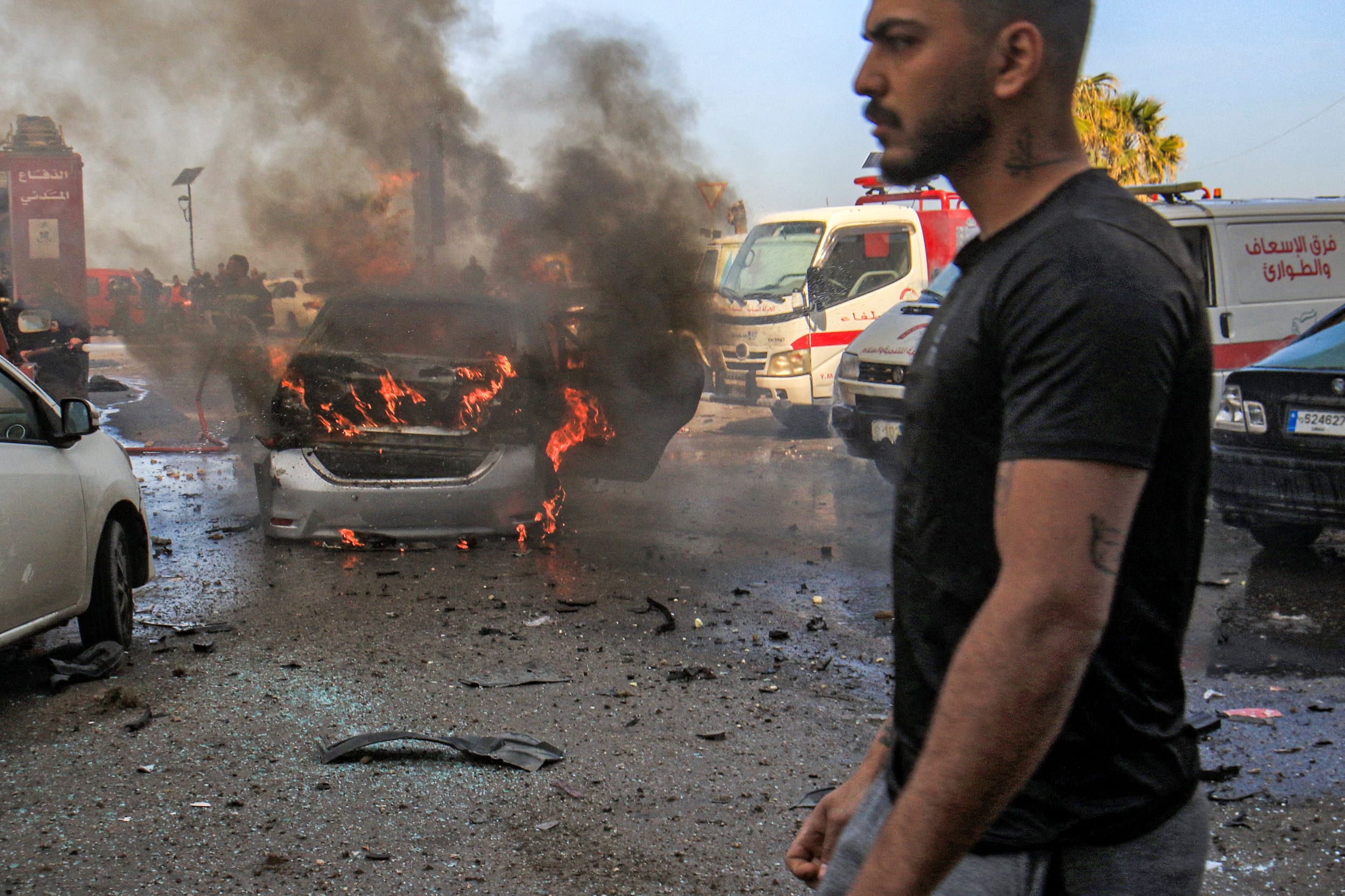 A man walks near a burning vehicle that was targeted by Israeli bombardment in Lebanon's southern coastal city of Sidon on March 18, 2026.