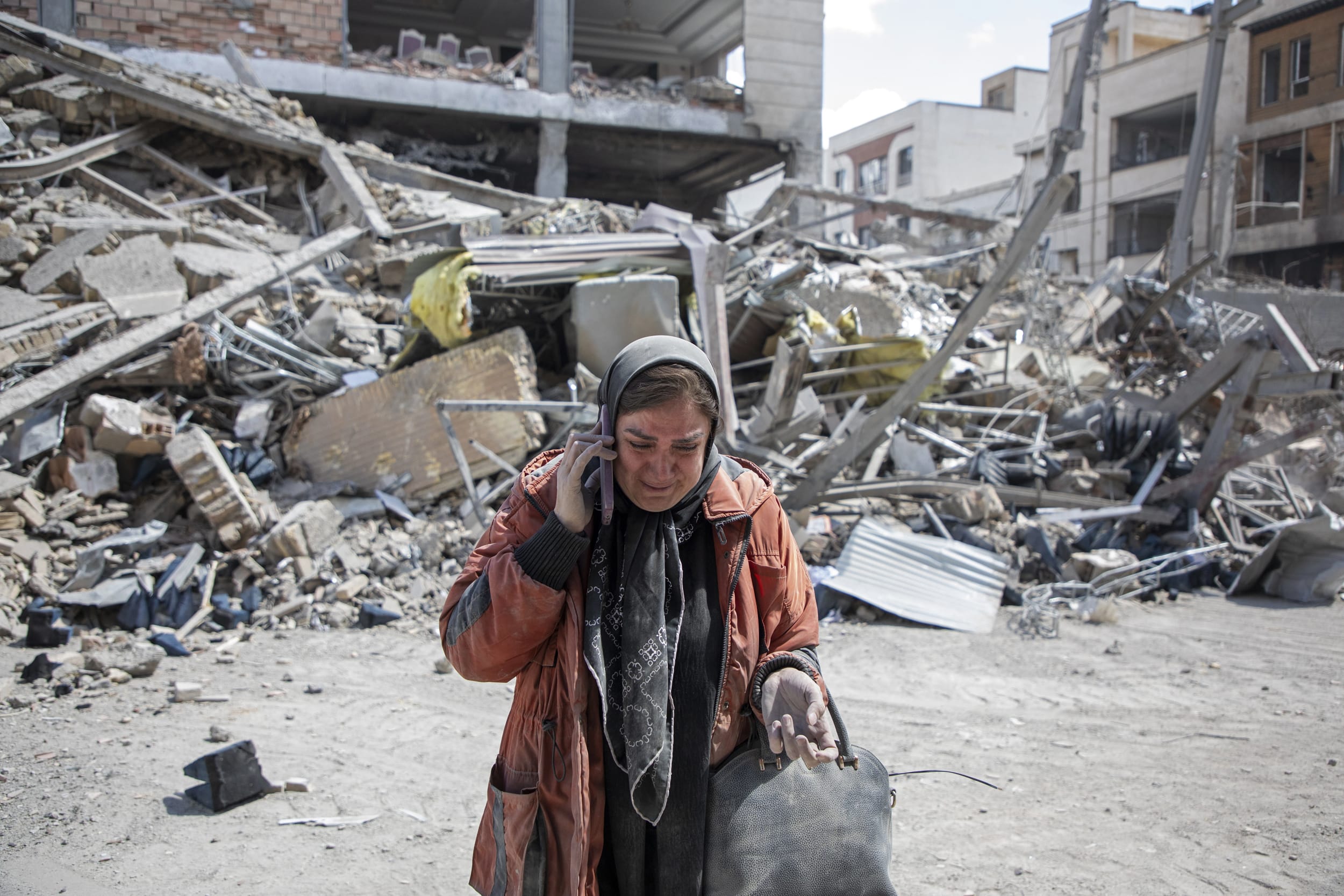 A resident weeps while talking on the phone near a residential building that was hit in an airstrike earlier this morning on March 30, 2026 in the west of Tehran, Iran.