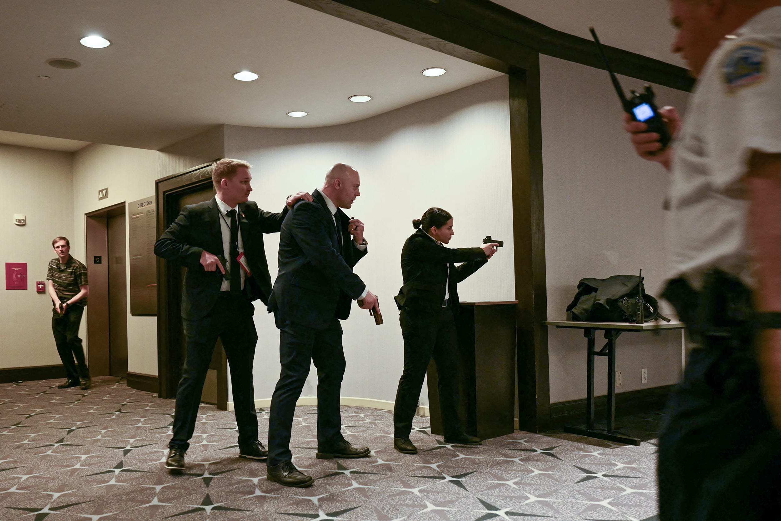 Four law enforcement agents in plainclothes with guns drawn in a conference room.