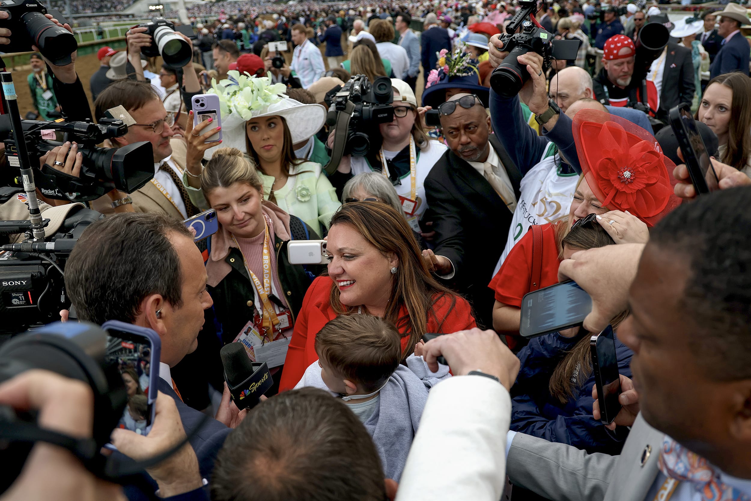 Cherie DeVaux smiles while surrounded by fans and reporters with cameras and microphones