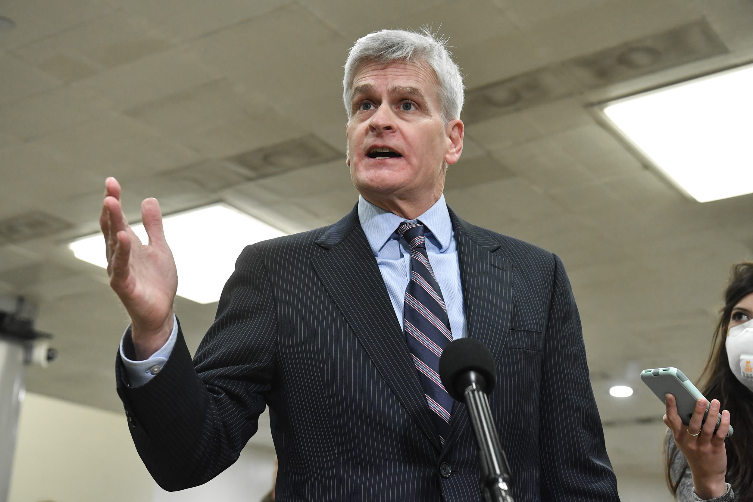 Bill Cassidy gestures with one hand while speaking into a microphone inside a U.S. Capitol building.
