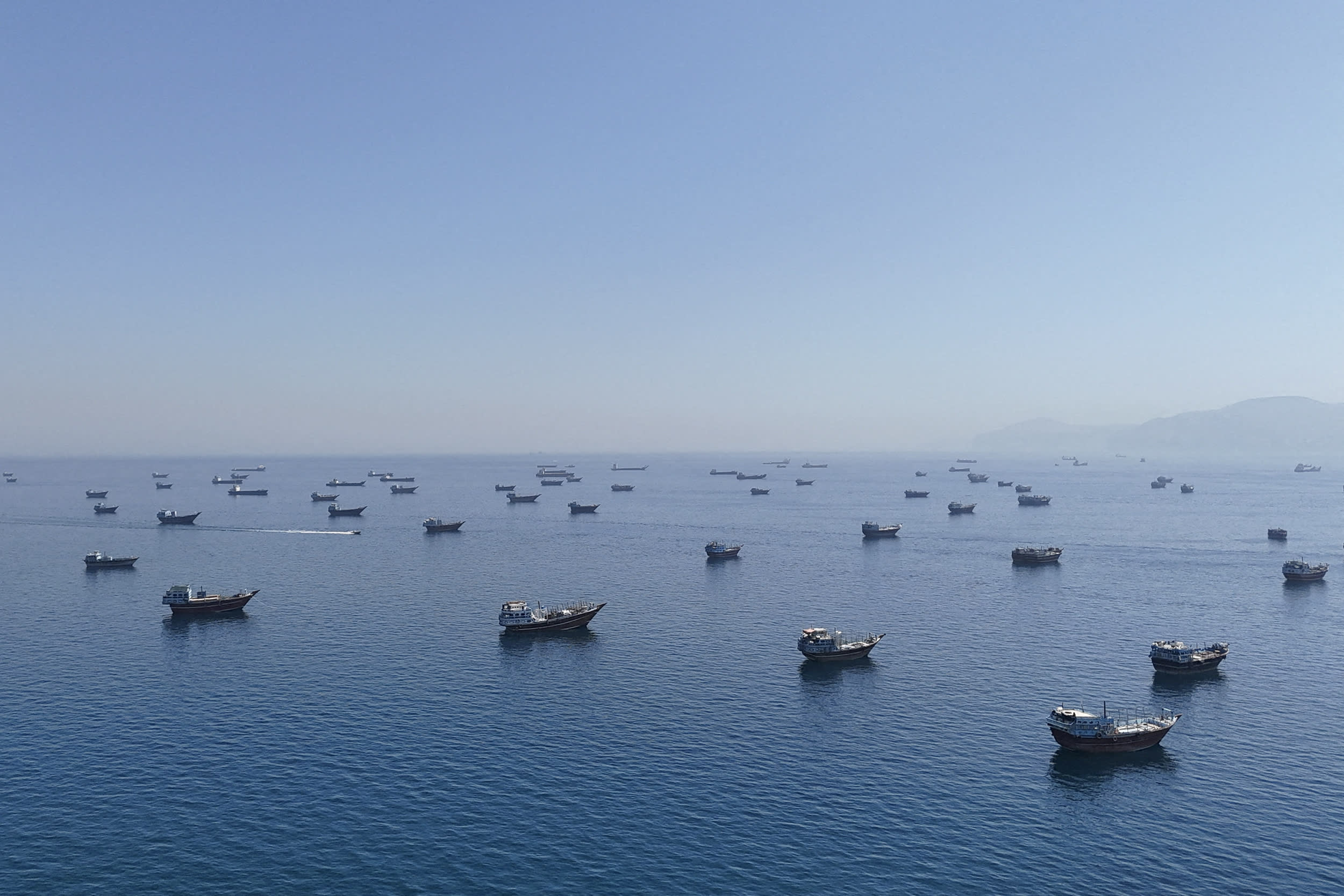 Dozens of vessels floating in blue waters.