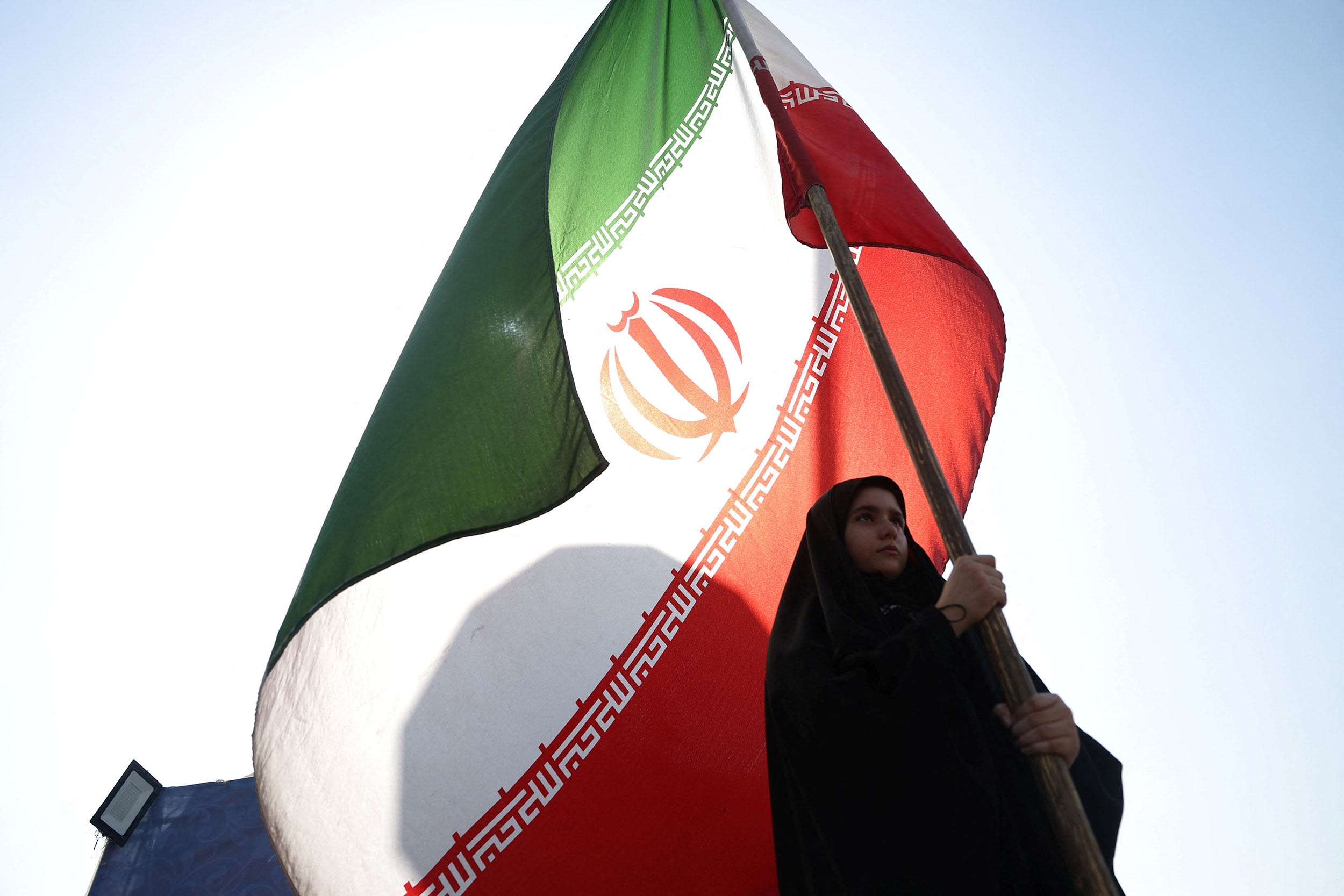 A woman holds an Iranian flag on a street in Tehran