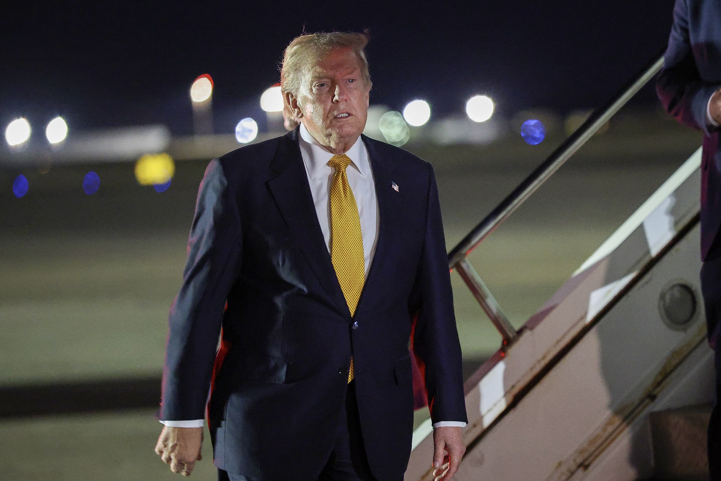 Donald Trump standing on a tarmac next to the stairs leading up to Air Force one.