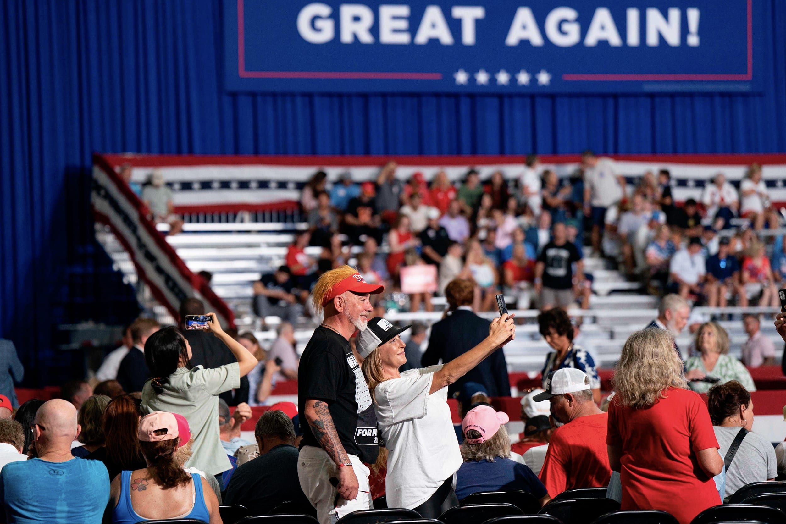 Two attendees take a selfie during a Trump rally.