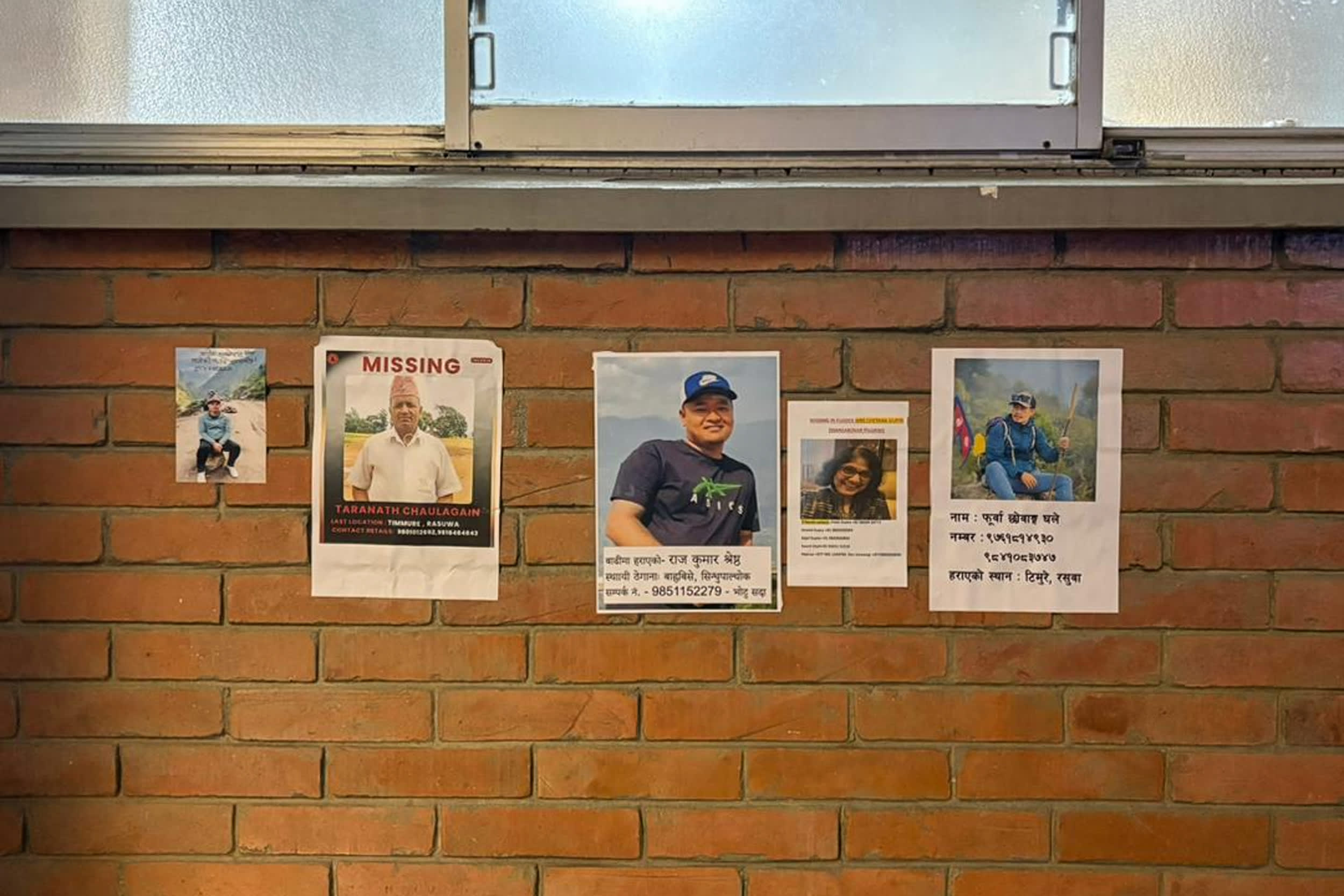 Five photographs taped to a brick wall to inform on missing people.
