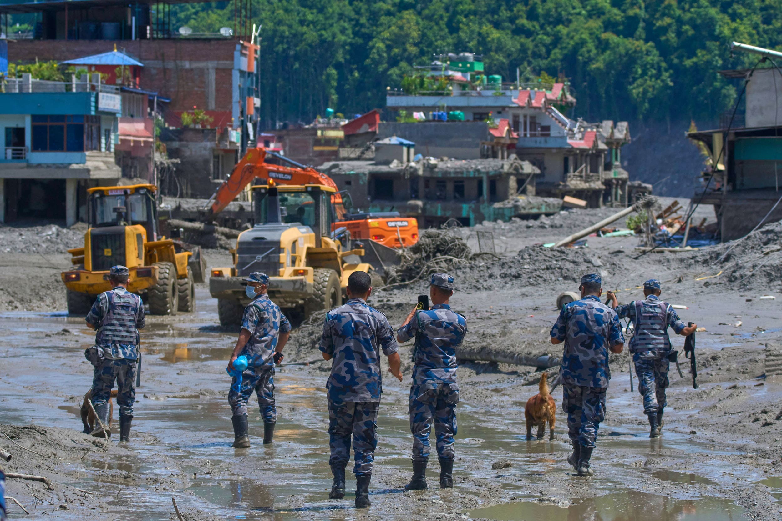 Police watch as earthmovers clear debris from flash flooding in Nepal's Nuwakot district, Thursday, Aug. 27, 2026. 