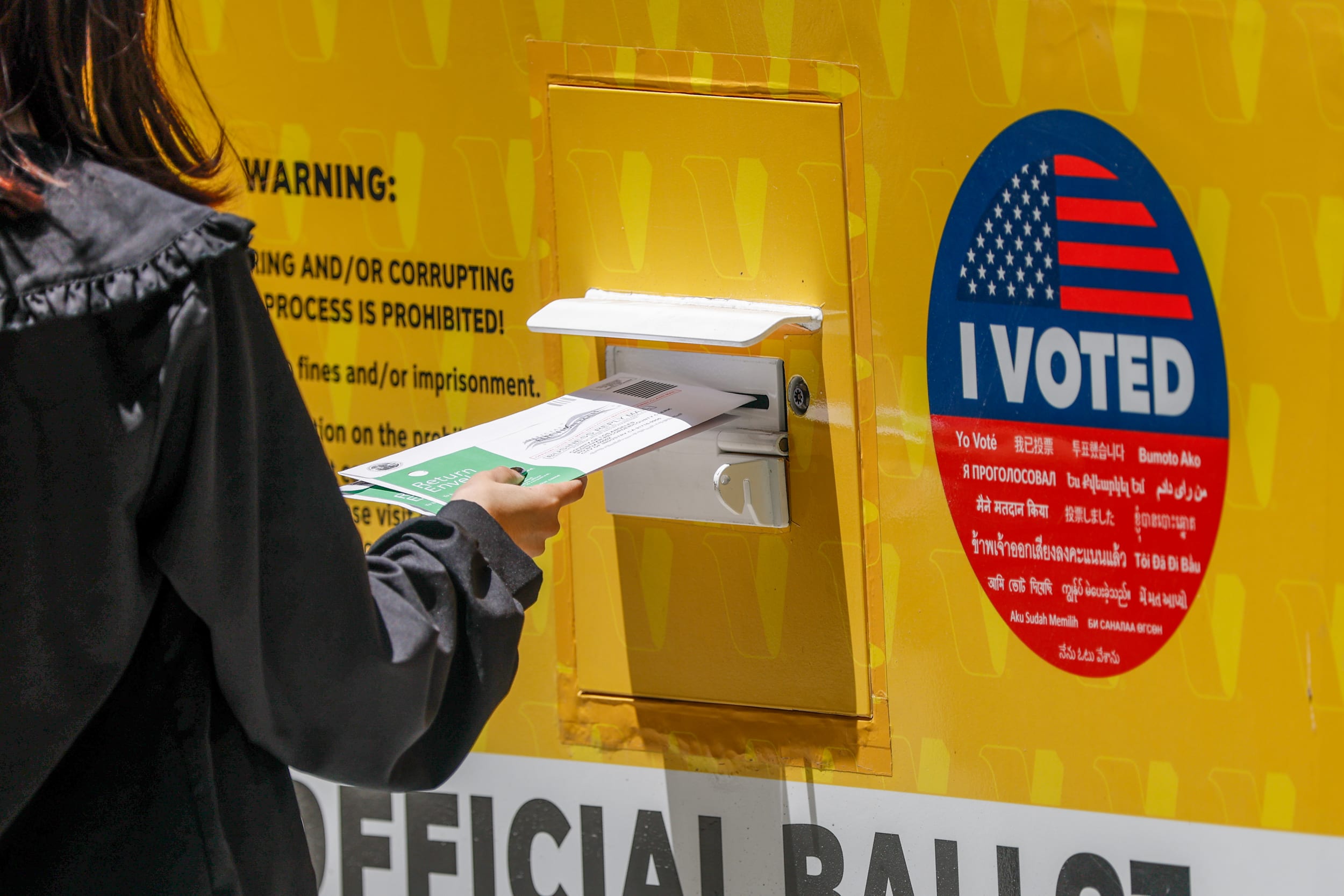 A person places their Mail in ballot into a ballot box.