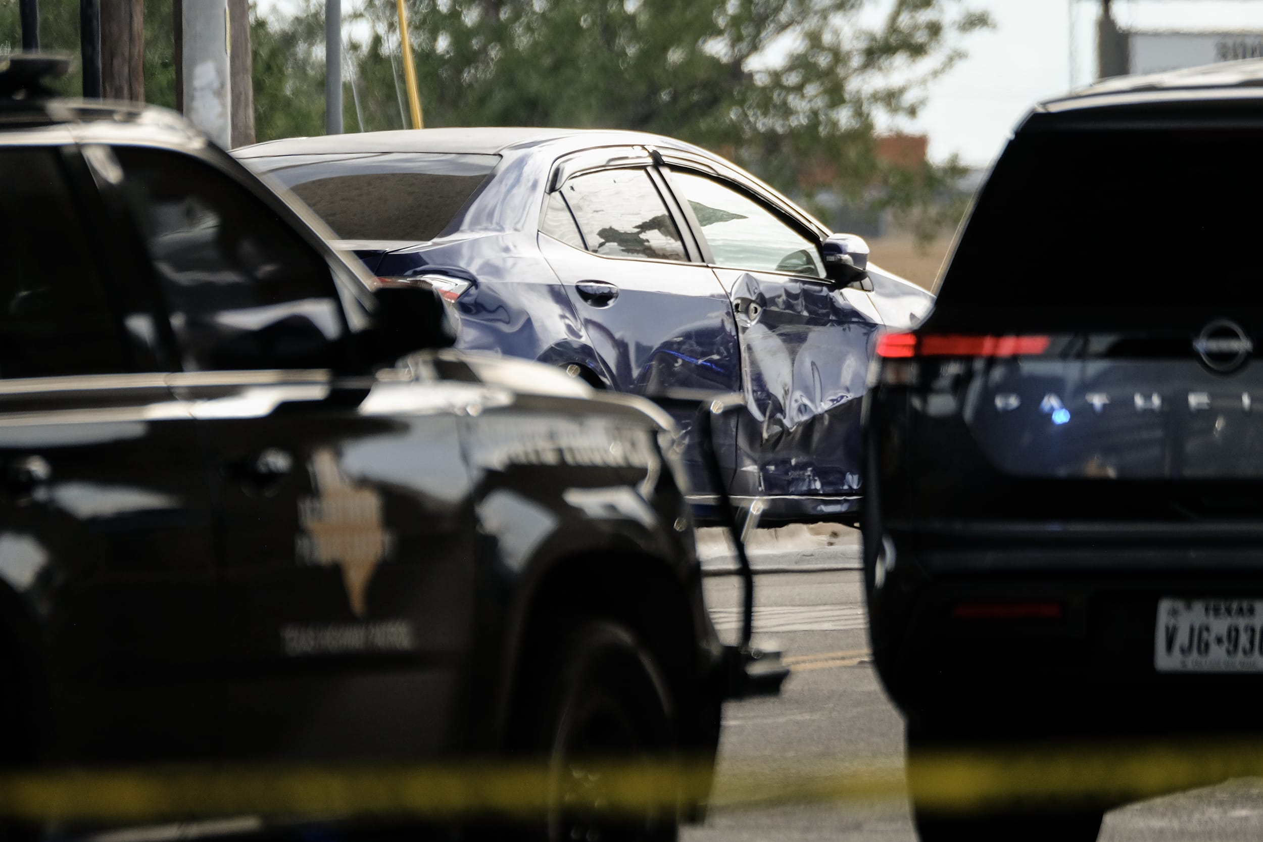 Bullet holes and scratches on the exterior of a blue sedan. 