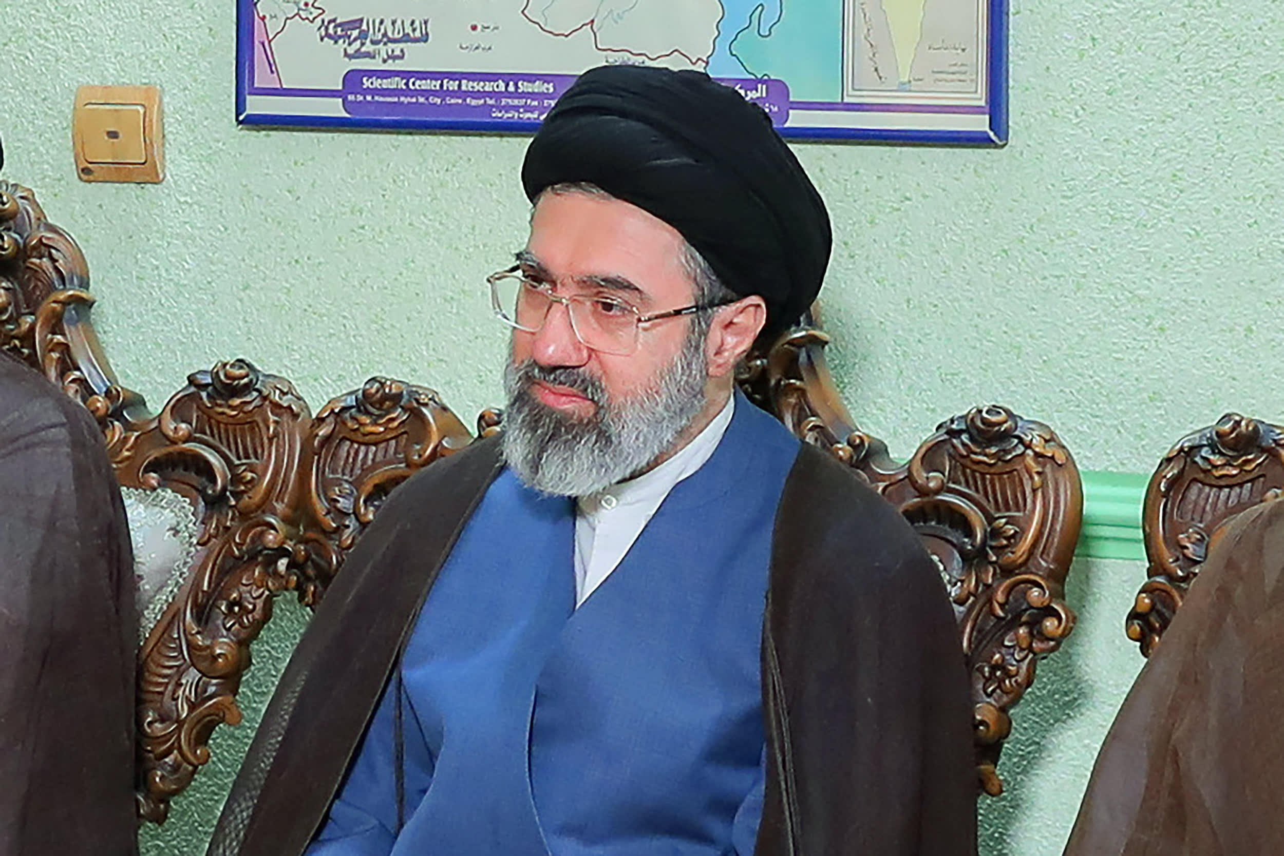 A photo of Mojtaba Khamenei seated in an ornate wooden chair.