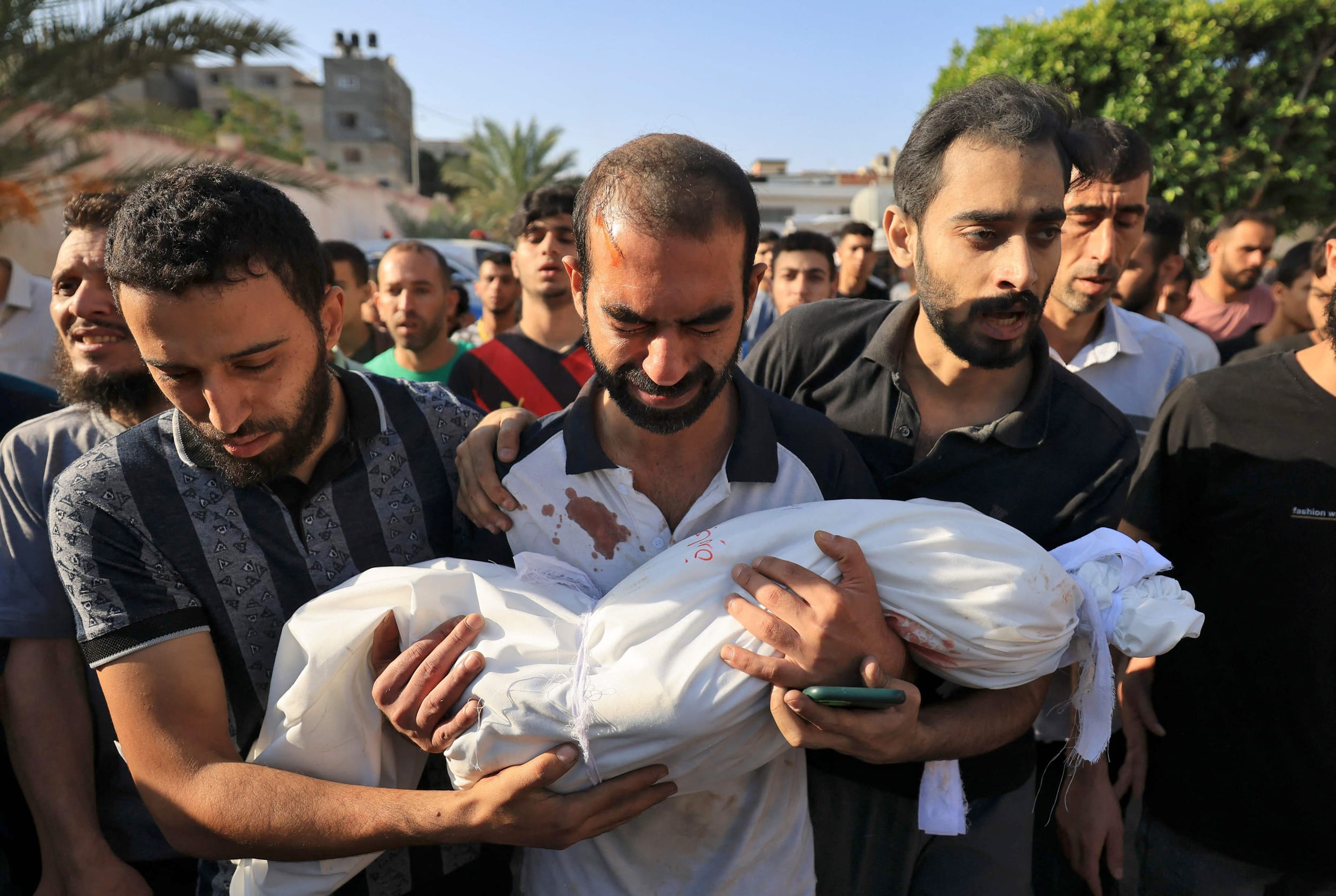 A father carries the body of his child killed in an airstrike during a funeral in Khan Yunis, southern Gaza Strip, on Oct. 19, 2023. 