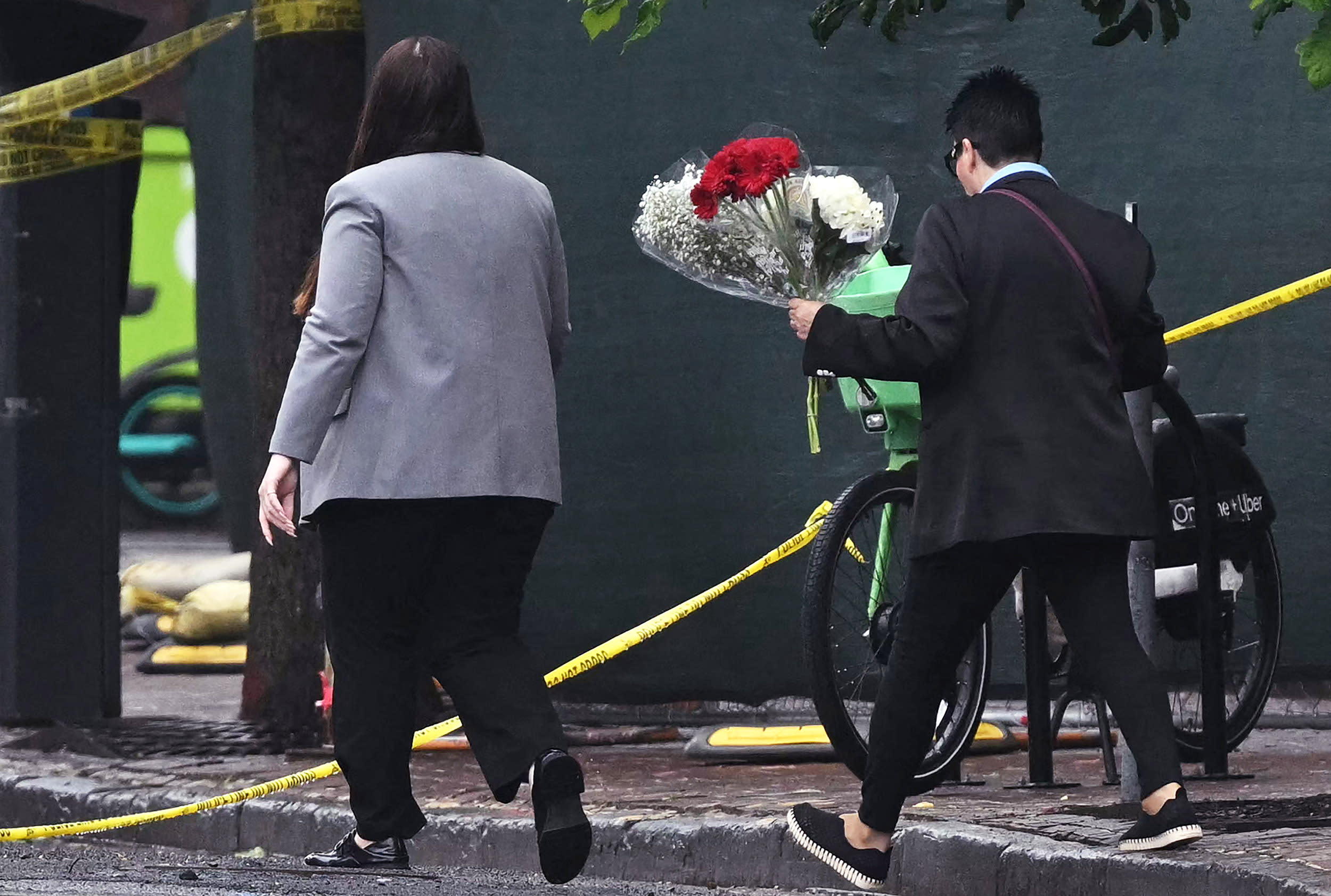 Two people deliver flowers to the crime site
