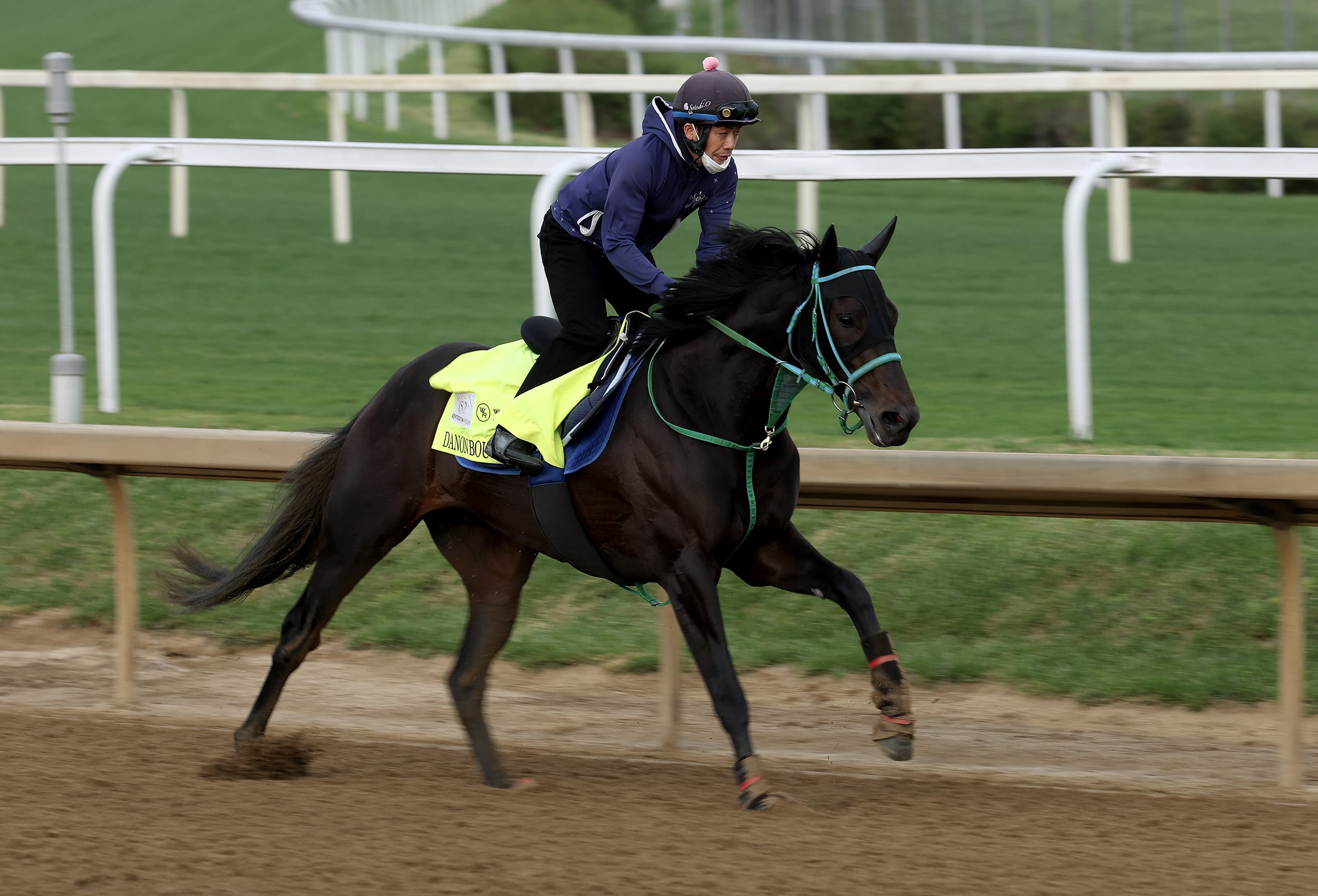 A jockey riding a horse on a dirt racetrack.
