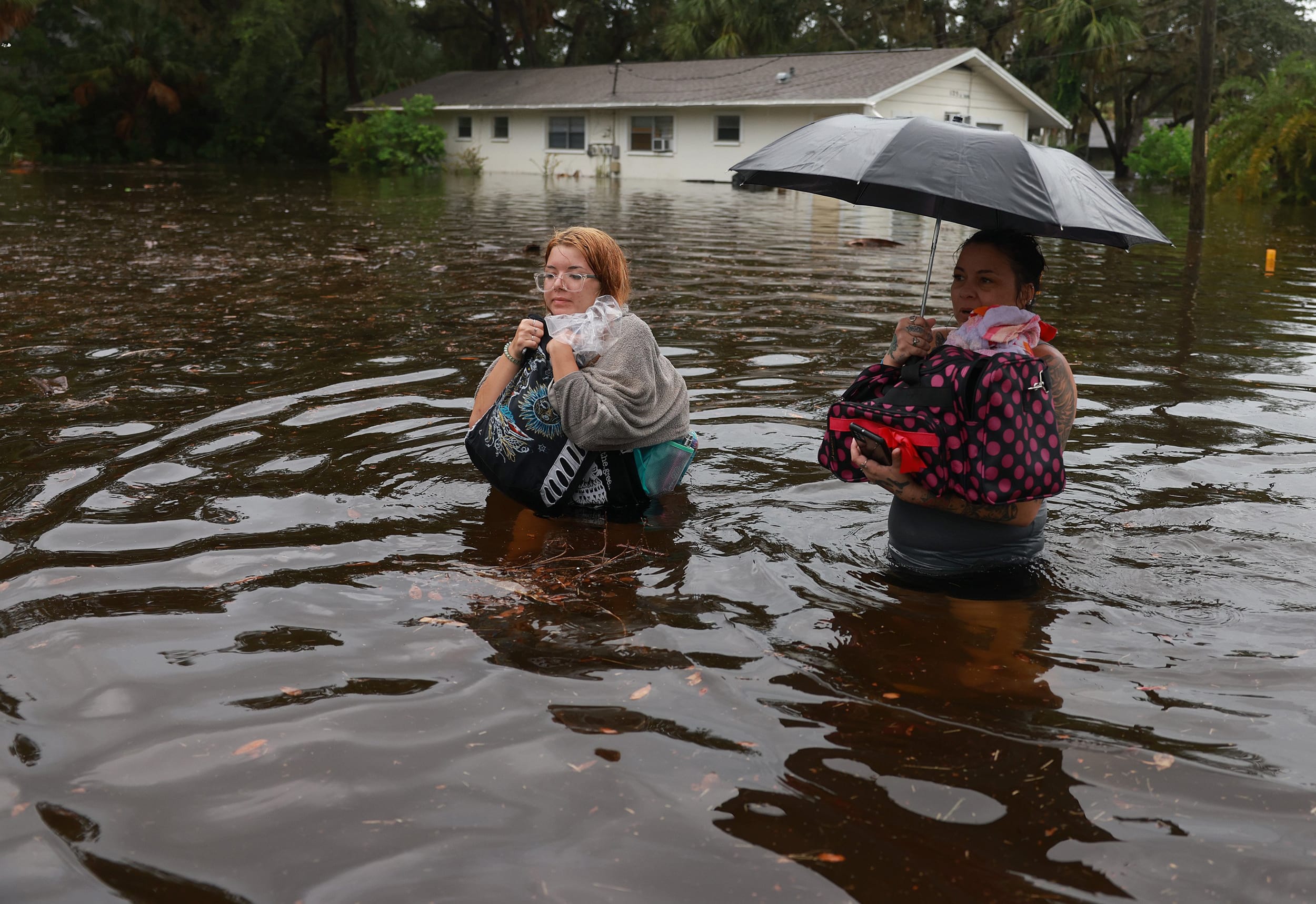 Makatla Ritchter, left, and her mother, Keiphra Line wade through flood waters in Tarpon Springs, Fla.