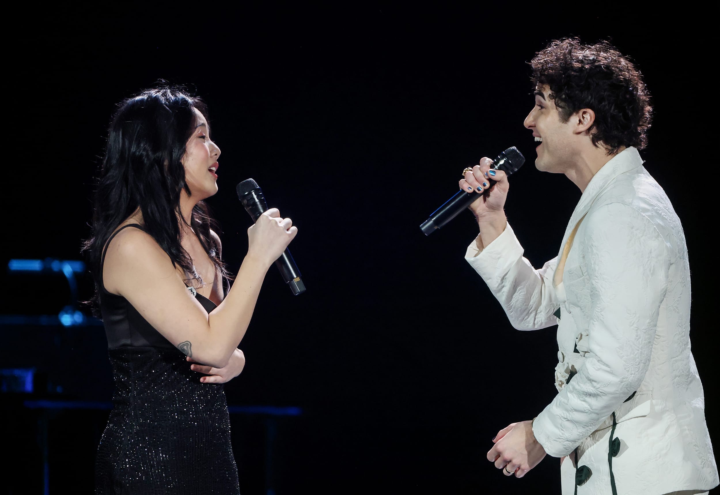 Helen J Shen and Darren Criss sing toward each other while performing onstage.
