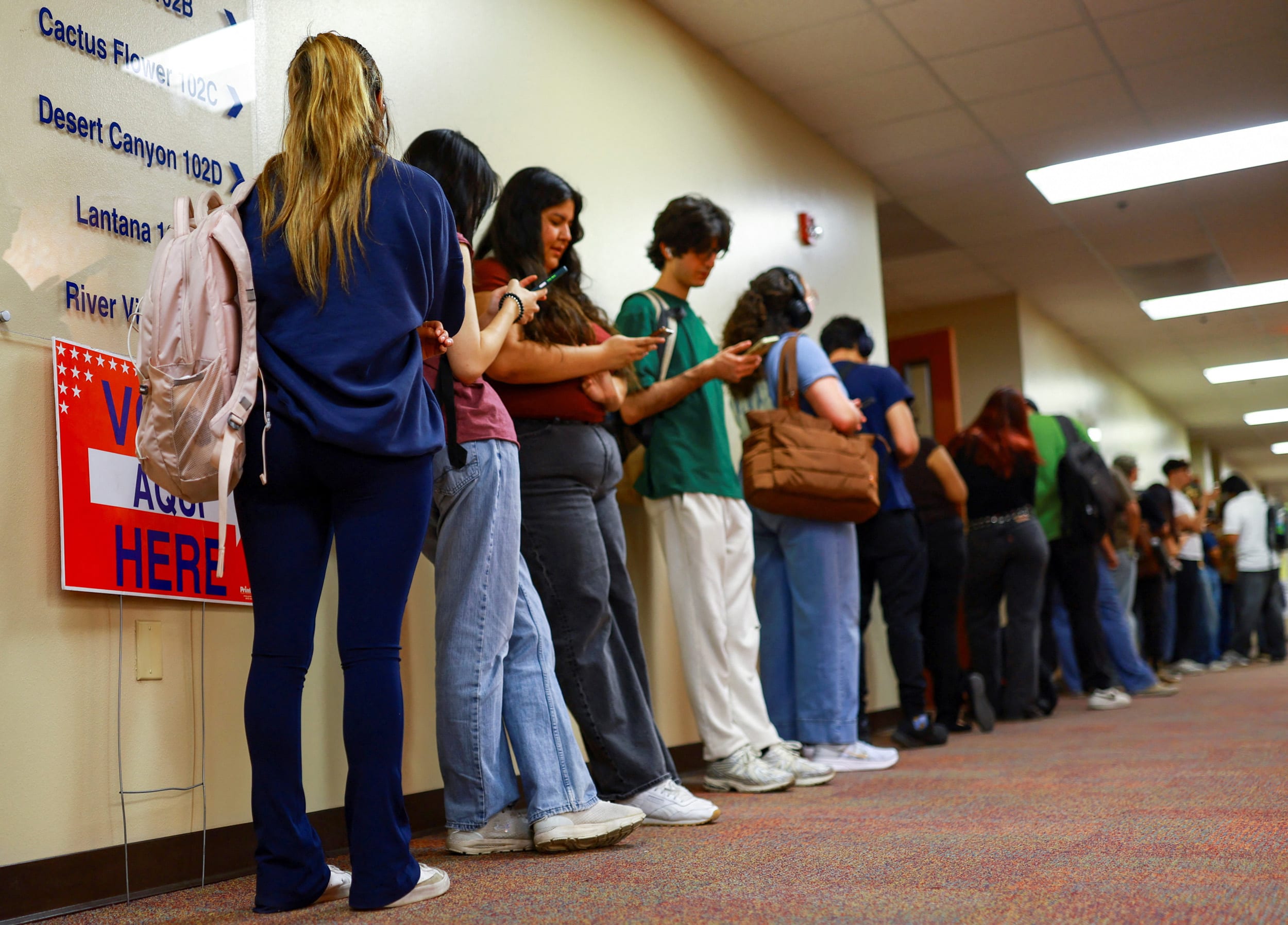 Students on line in a hallway next to "Vote Here" signs.