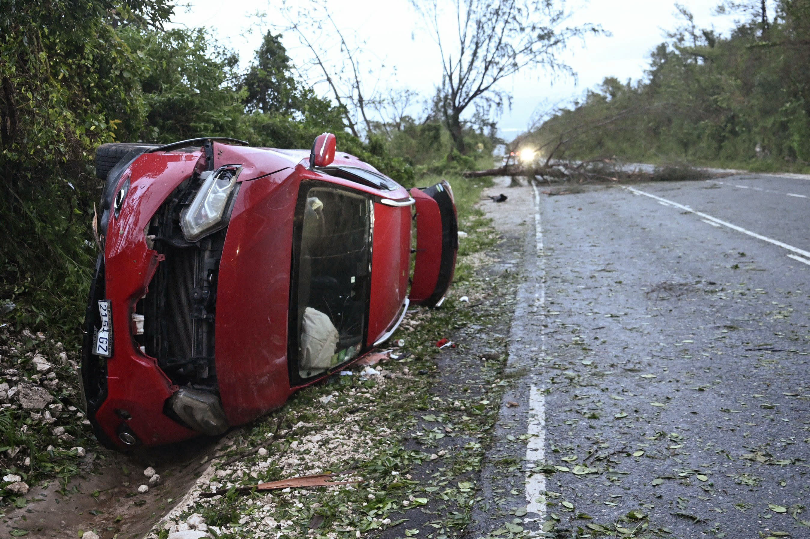 A car lies on its side by a fallen tree after the passage of Hurricane Melissa in Manchester, Jamaica, on October 29, 2025.