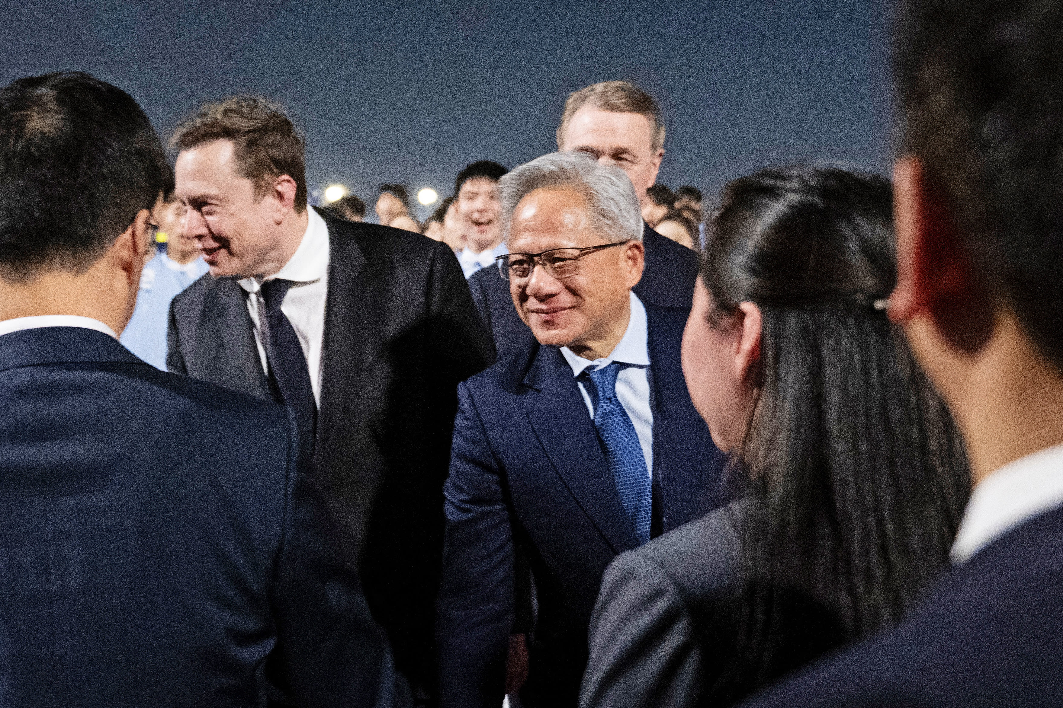 Elon Musk and Nvidia President and CEO Jensen Huang, center, are greeted as they arrive at the Beijing Capital International Airport May 13, 2026. 