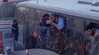 Child embraced by freed Palestinian prisoner as buses arrive in Gaza