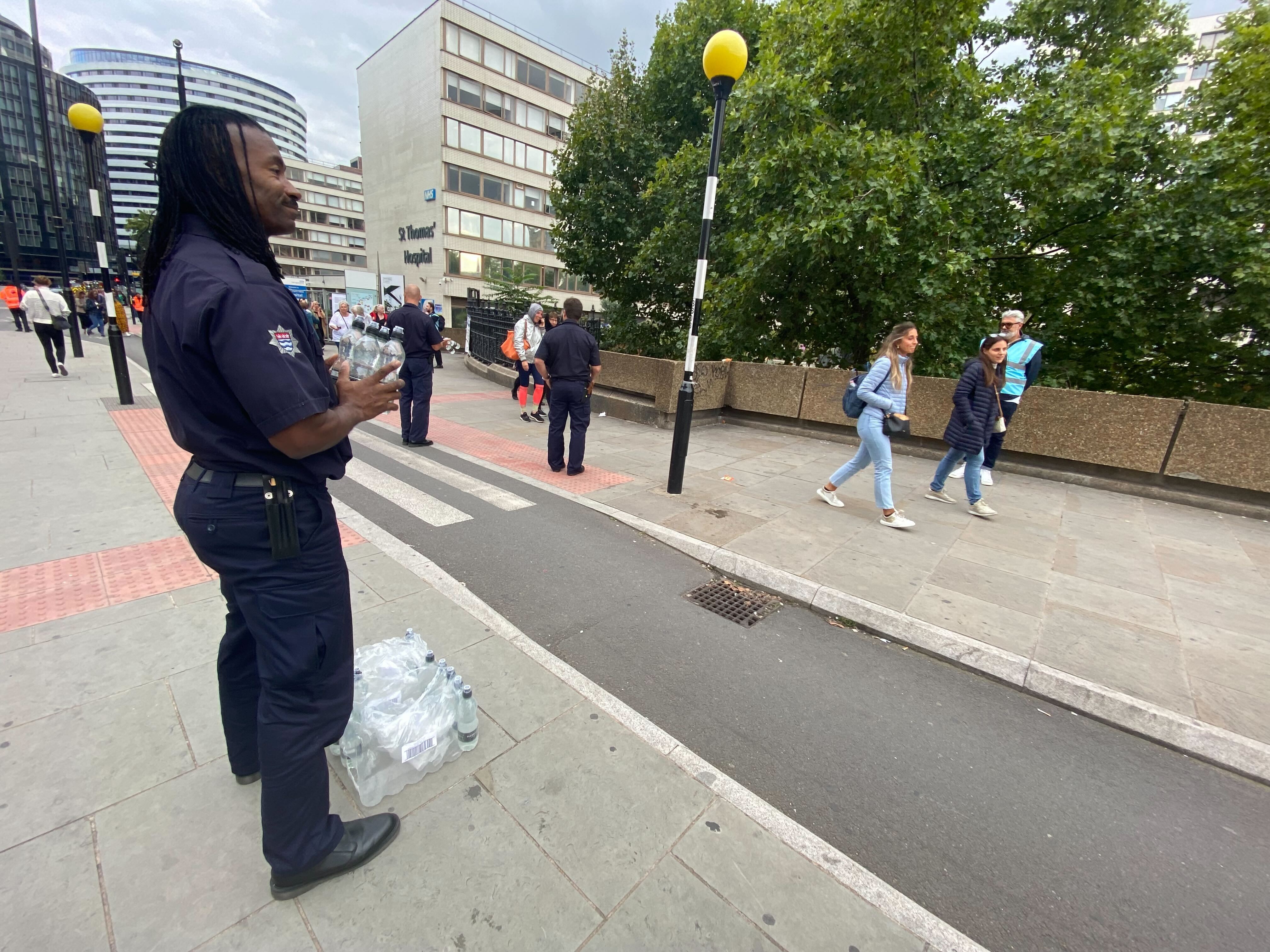 A member of the London Fire Brigade hands out water to people joining the line to pay respects to the queen.