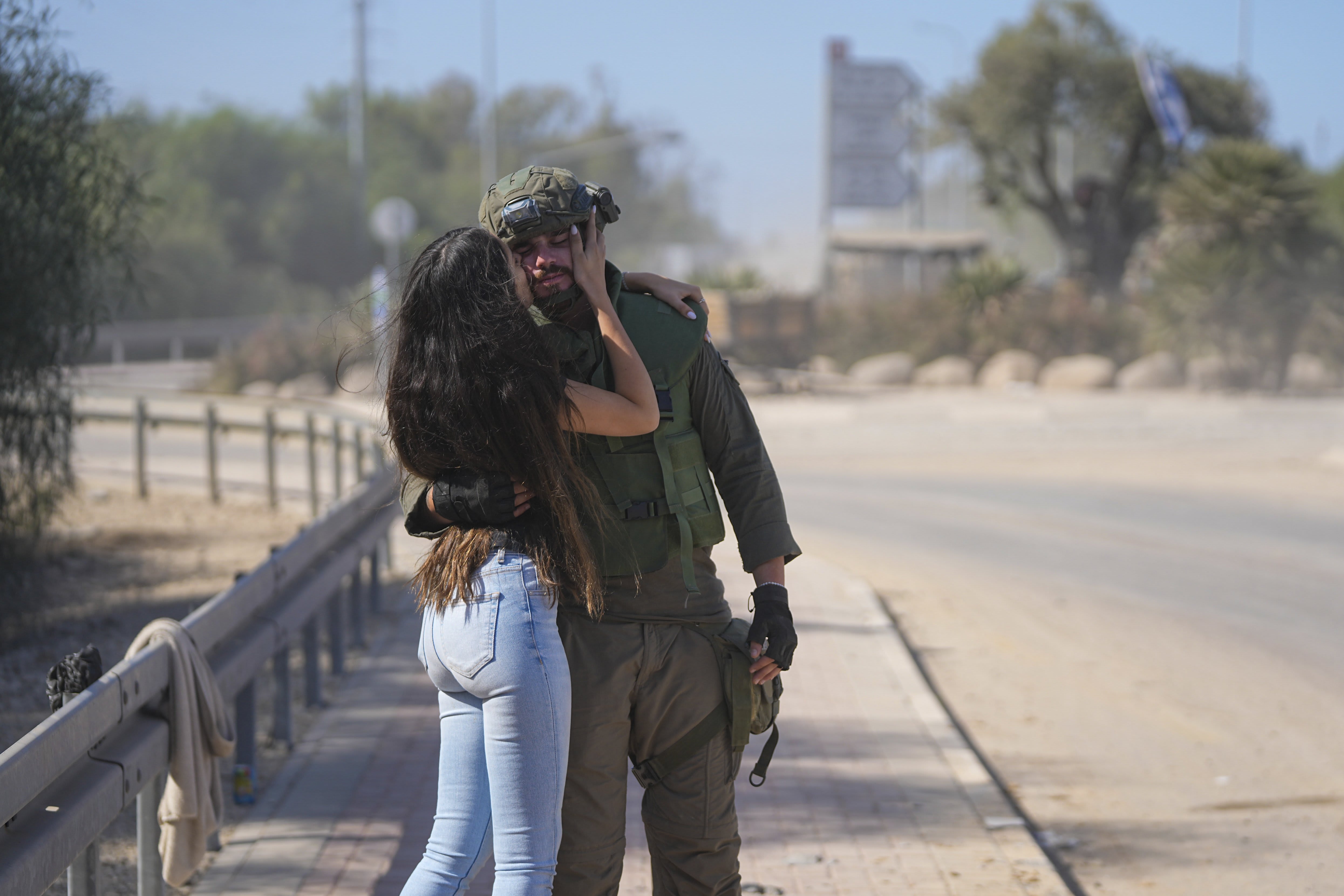 An Israeli soldier is kissed by his partner as she visits him near the border with the Gaza Strip, southern Israel, on Friday, Oct. 20, 2023. 