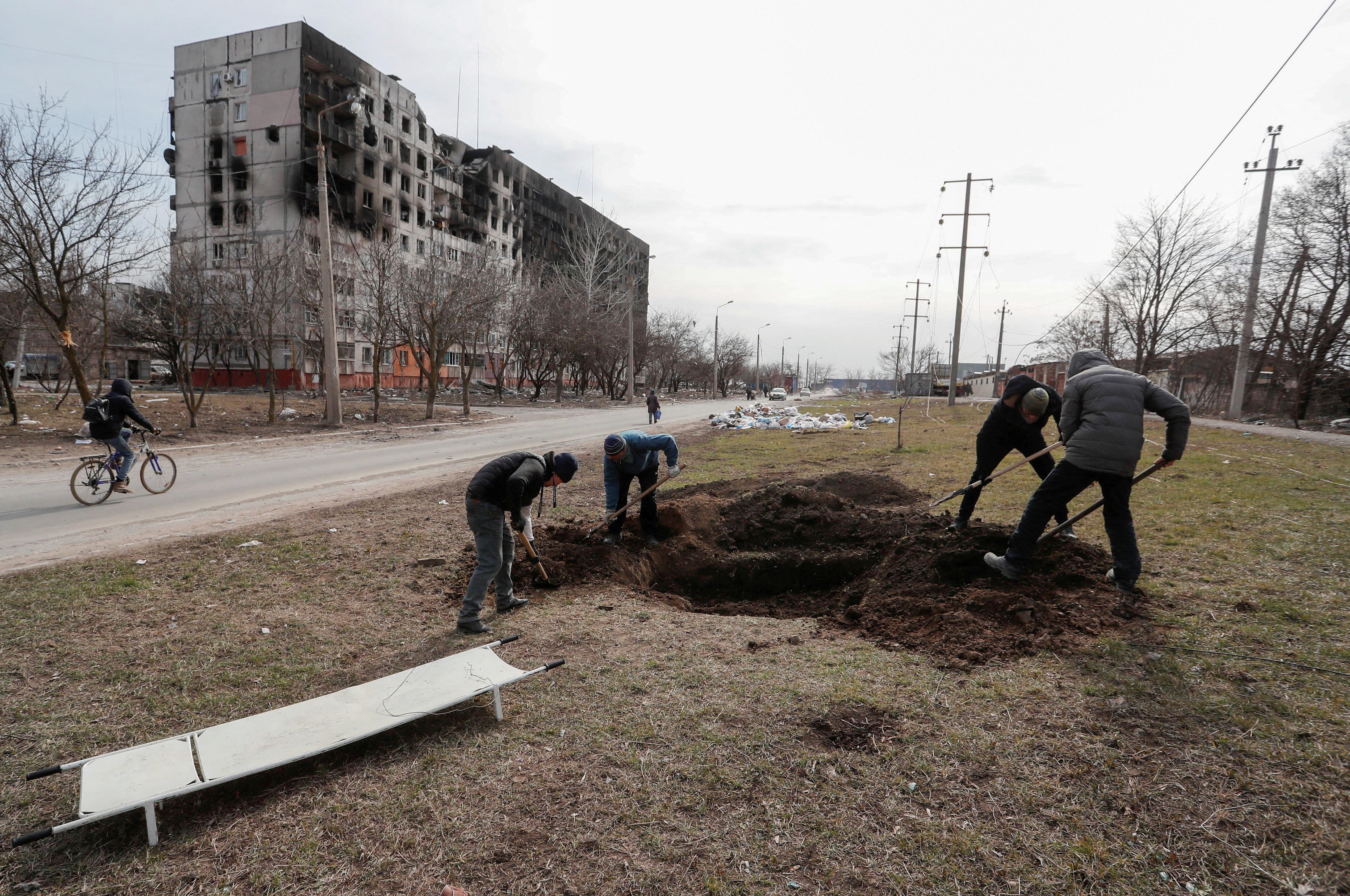 People dig a grave for victims killed during Ukraine-Russia conflict in a street in the besieged southern port city of Mariupol, Ukraine on March 20, 2022.